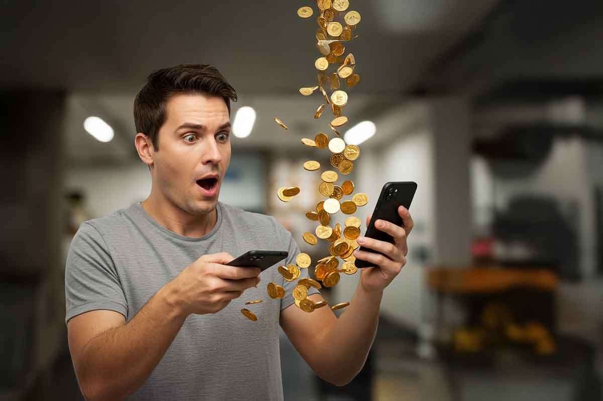 スマートフォンからお金が出てきて驚く男性