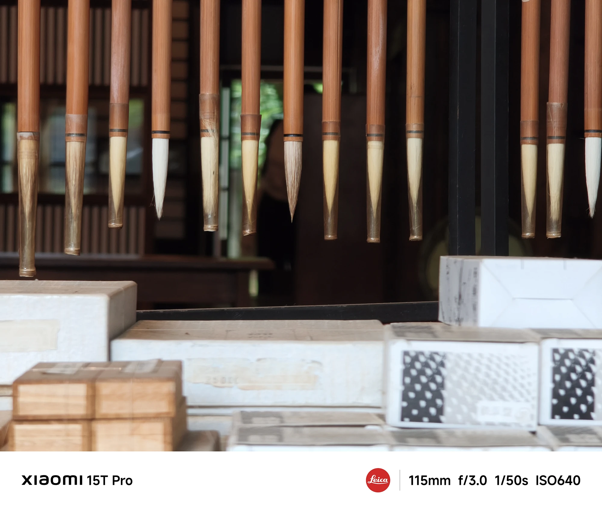 Xiaomi 15T Proで撮影した吊り下げ筆と書道用品のクローズアップ（115mm望遠、低照度作例）