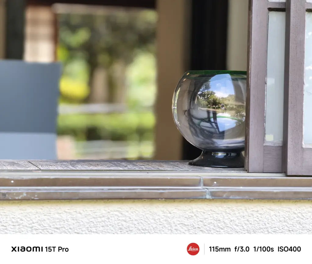 Xiaomi 15T Proで撮影した窓辺のガラス器に反射する風景のクローズアップ（115mm望遠作例）