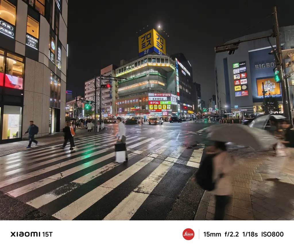 Xiaomi 15Tの超広角カメラで撮影した夜の交差点。傘を差す人々と街の光が交錯し、Leica Authentic特有の陰影表現が美しい
