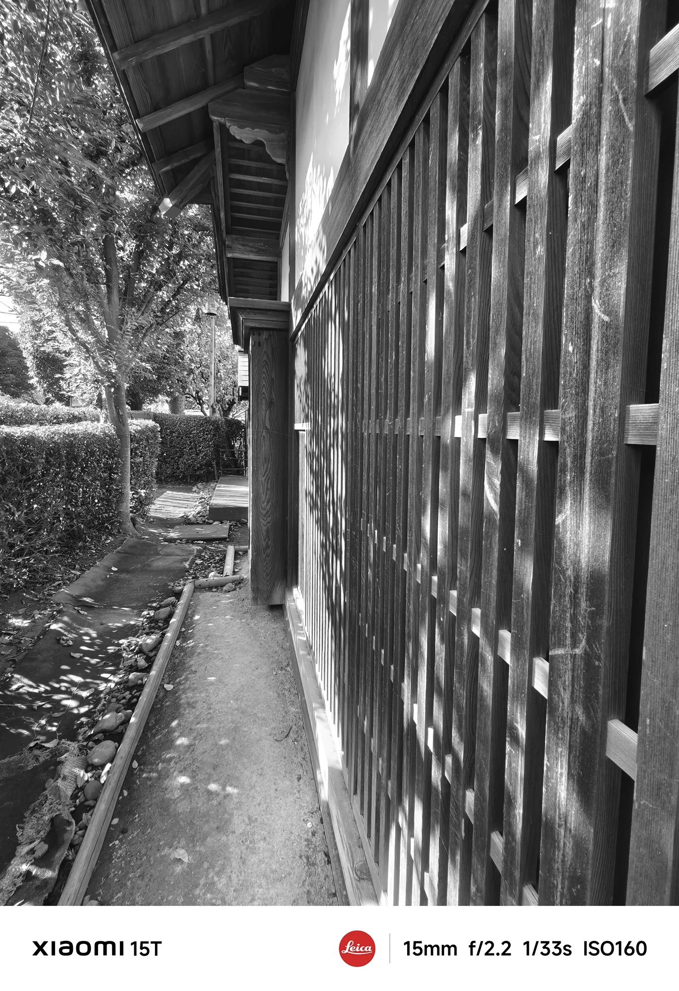 Xiaomi 15TのLeicaモノクロフィルターで撮影した日本家屋の外壁。木漏れ日が格子に落ち、陰影豊かな情景を描き出す