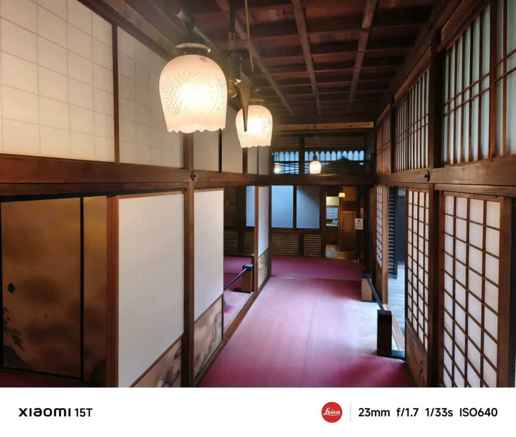 Xiaomi 15Tのメインカメラで撮影した和風建築の廊下。柔らかな照明が木の梁や障子に反射し、落ち着いた雰囲気を演出