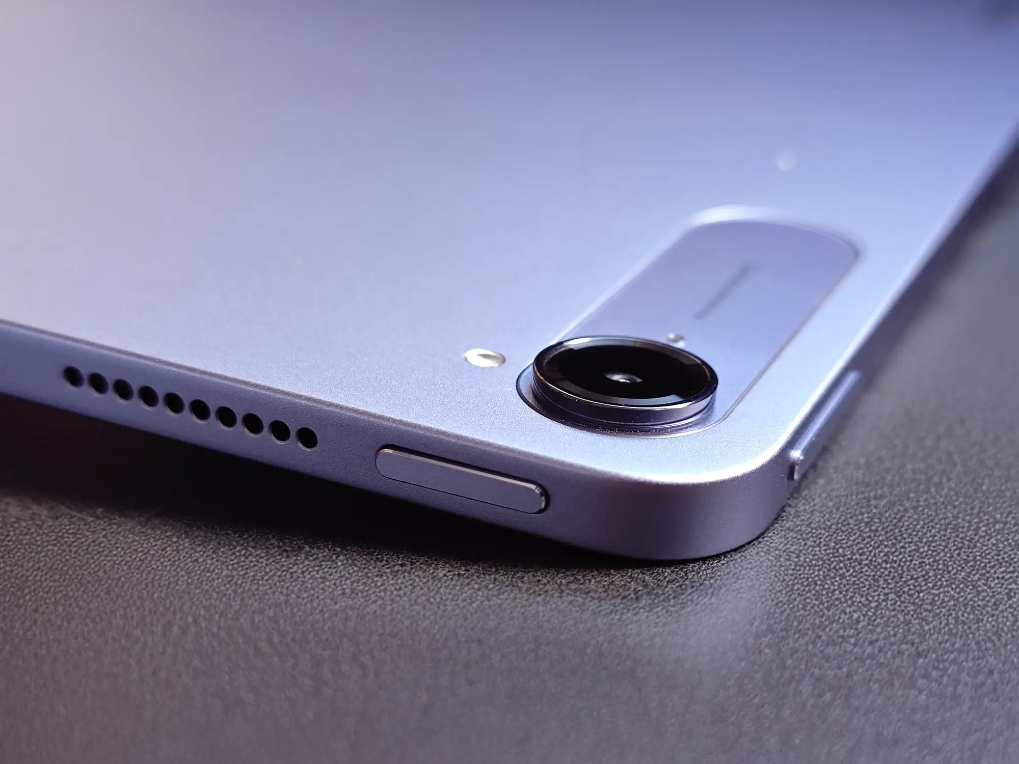 パープル/ブルーグレー系のタブレットの背面カメラ、スピーカー穴、側面ボタン(電源/ボリューム)をクローズアップ。丸みを帯びたデバイスの角のディテール。