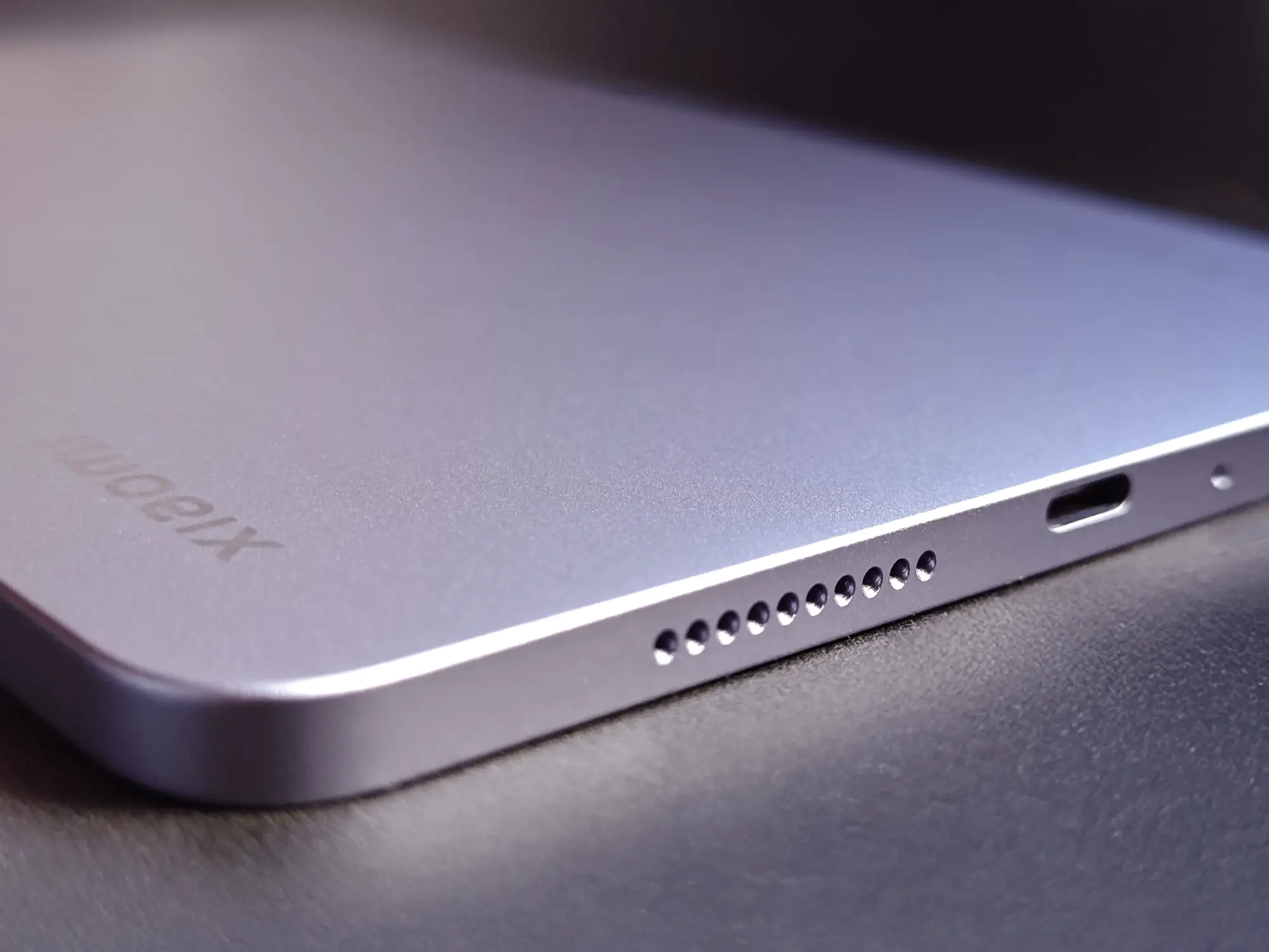 Xiaomi製タブレット側面のクローズアップ。スピーカー穴とUSB Type-Cポートのディテール。パープル/ブルーグレーの筐体の質感も見える。