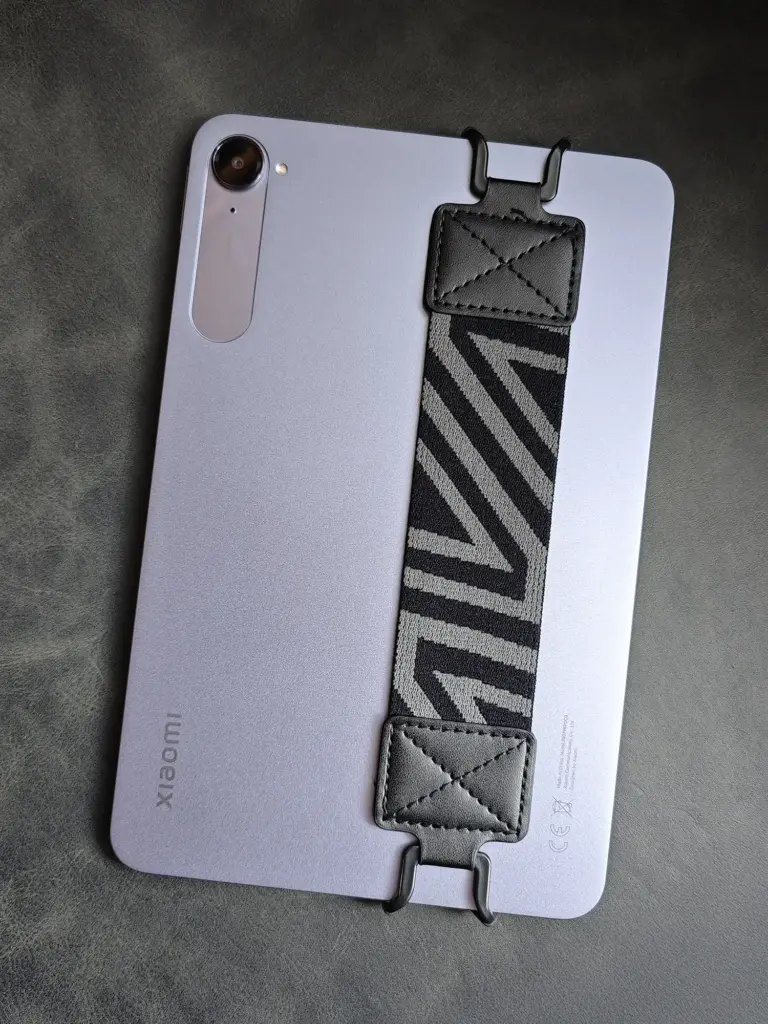 Xiaomi Pad Miniの背面に、斜めストライプ柄のハンドストラップ（ハンドグリップ）がフックで取り付けられている写真。片手での操作安定性を高めるためのタブレットアクセサリー。