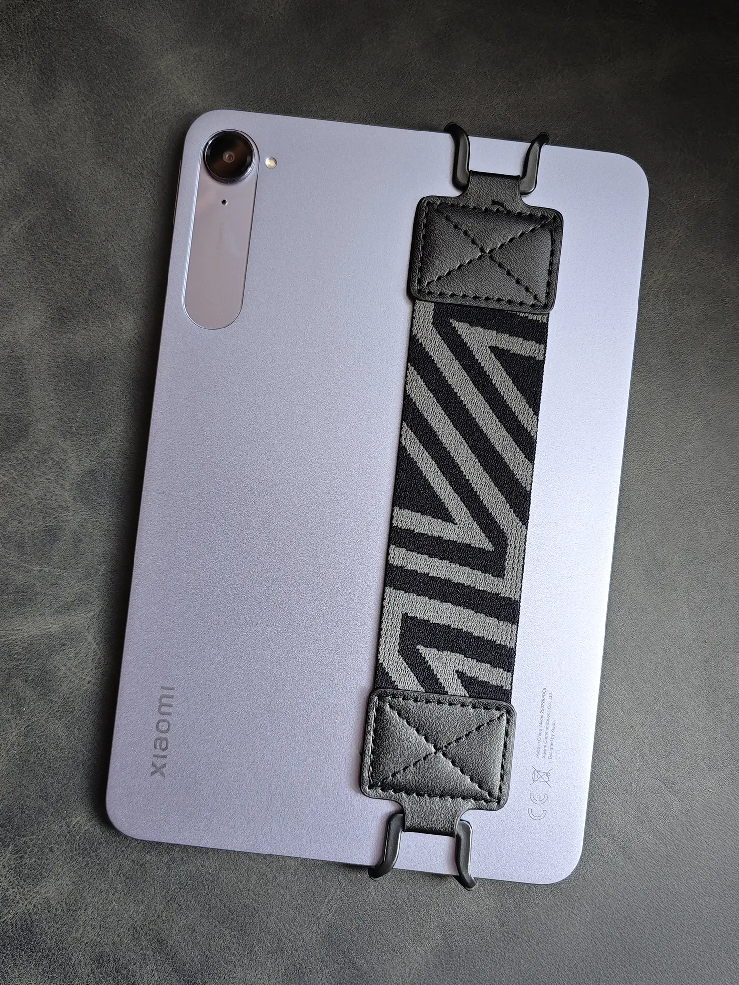 Xiaomi製タブレットの背面に、斜めストライプ柄のハンドストラップ(ハンドグリップ)がフックで取り付けられている写真。片手での操作安定性を高めるためのタブレットアクセサリー。