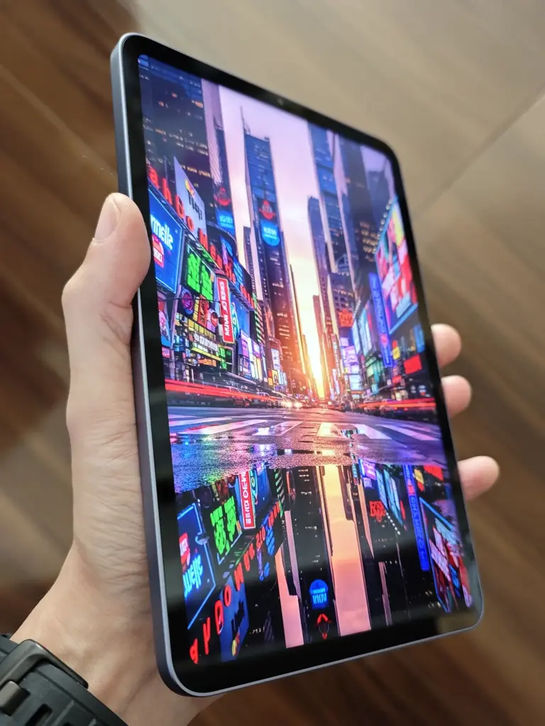 手で持ったXiaomi Pad Miniのディスプレイに表示された、ネオンサインと高層ビルの鮮やかな夜の都市風景写真。水たまりに光が反射し、高コントラストな発色が強調されている。