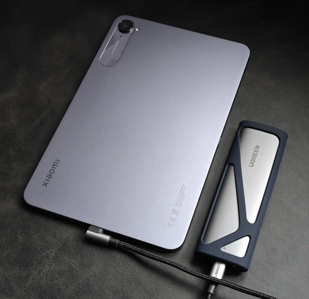 Xiaomi Pad Miniに、UGREEN 製の USB Type-C 外付け SSD ケース（または M.2 SSD ハブ）を接続している背面写真。タブレットのカメラと SSD ケースのデザイン比較。