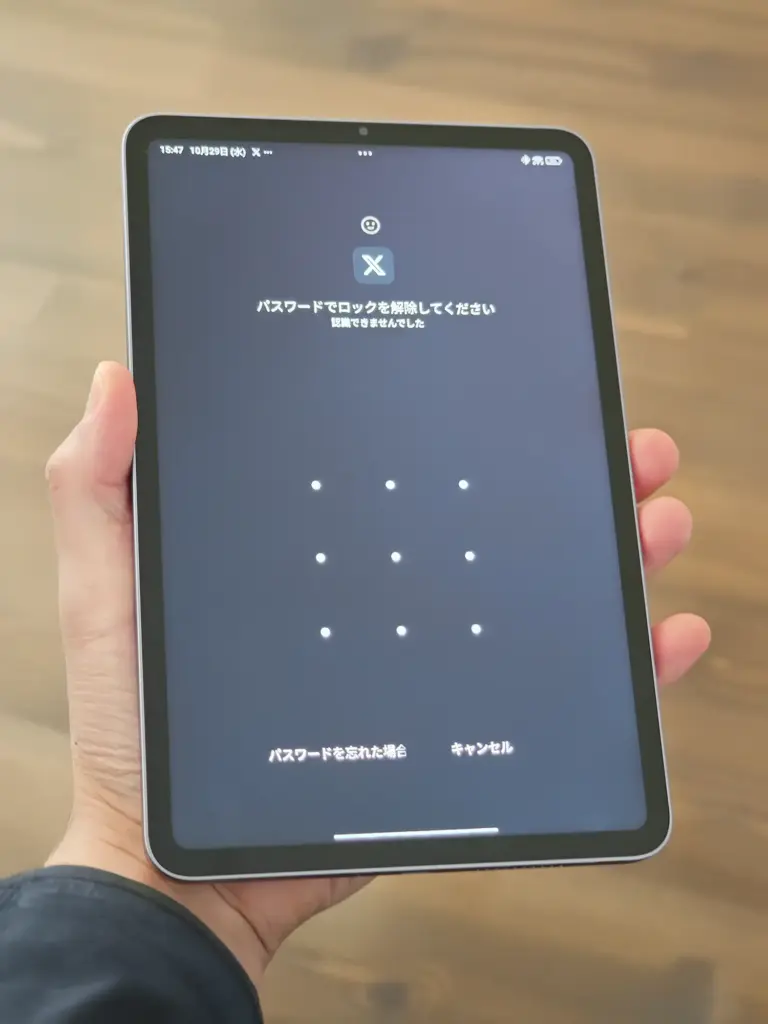 手に持ったXiaomi Pad Miniに表示された、X（旧 Twitter）アプリのロック解除画面。パターン入力と「パスワードでロックを解除してください」のメッセージが表示されている。