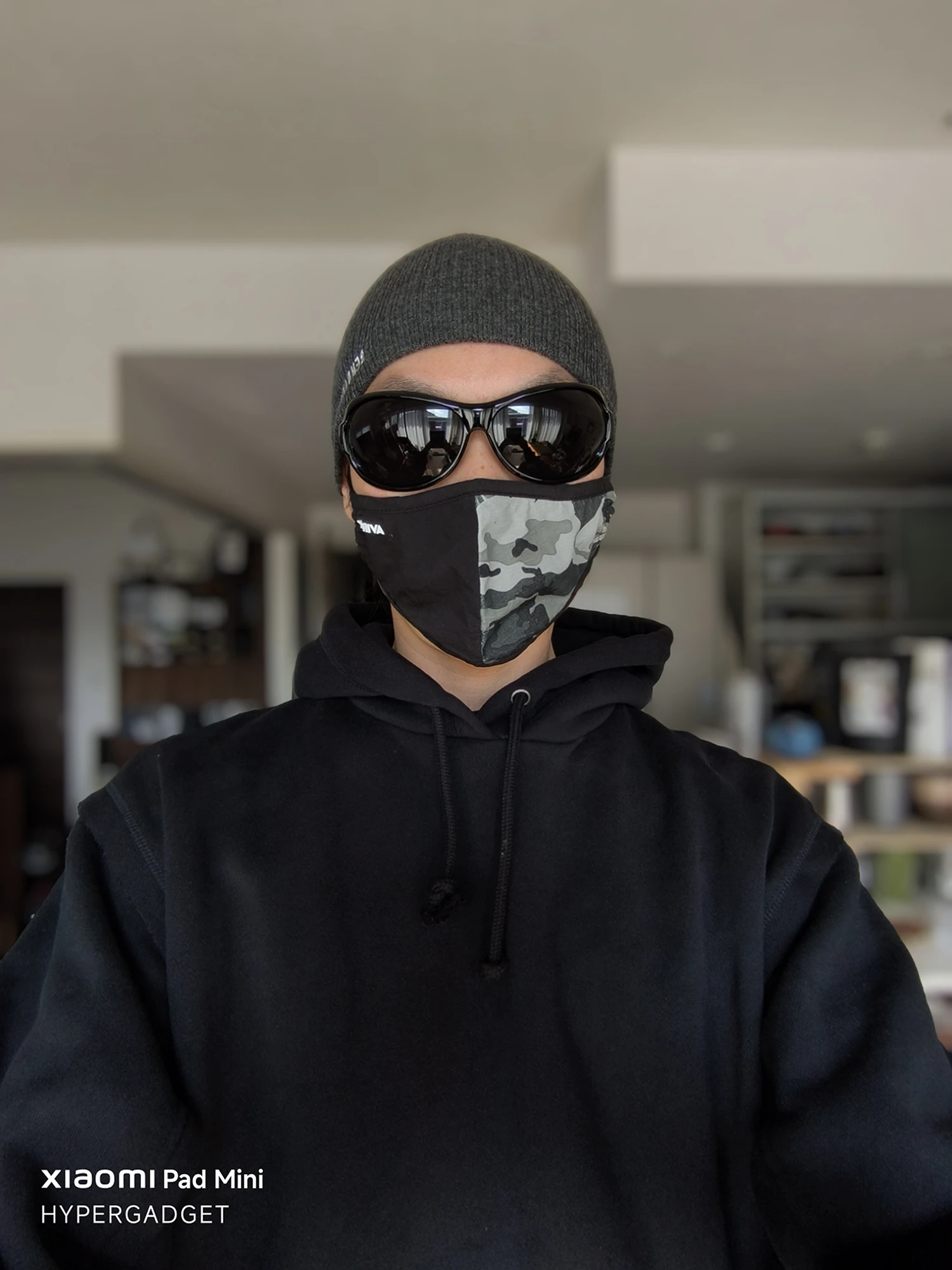 Xiaomi Pad Miniで撮影された、サングラスとニット帽、迷彩マスクを着用した人物の正面ポートレート作例。屋内を背景に適度にボケが表現されている。