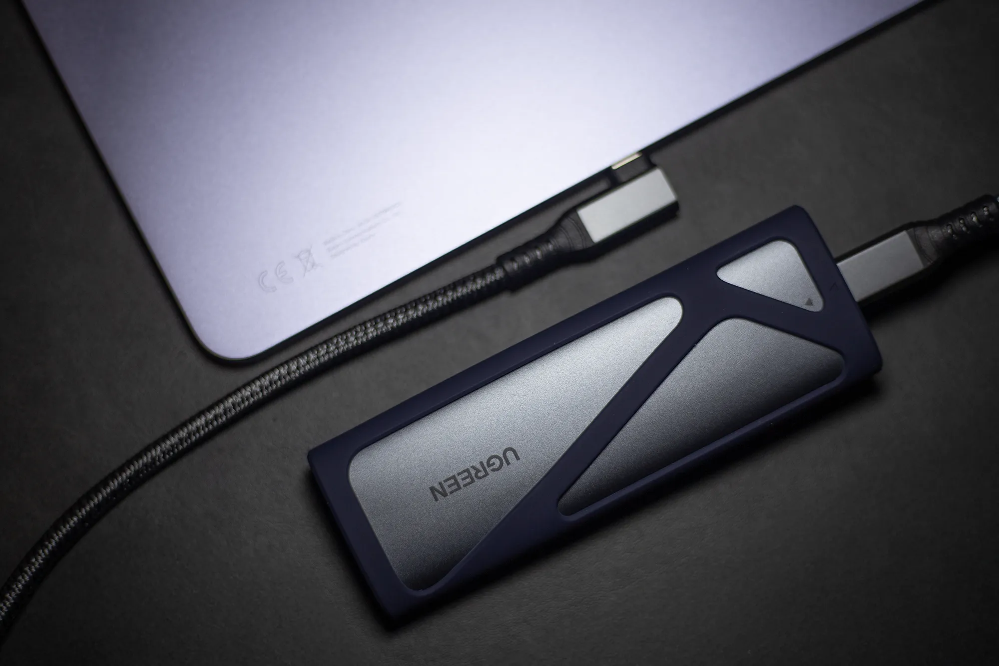 UGREEN製の外付けM.2 SSDケース(NVMe/SATA)を、USB Type-CケーブルでノートPCに接続している写真。高速データ転送の利用シーン。