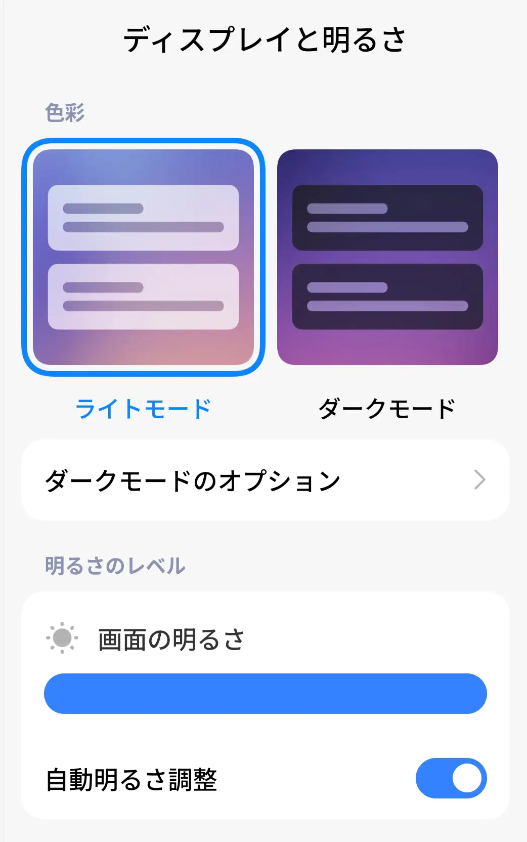 「ディスプレイと明るさ」設定画面のスクリーンショット。ライトモードとダークモードの選択肢、画面の明るさスライダー、自動明るさ調整のスイッチが表示されている。