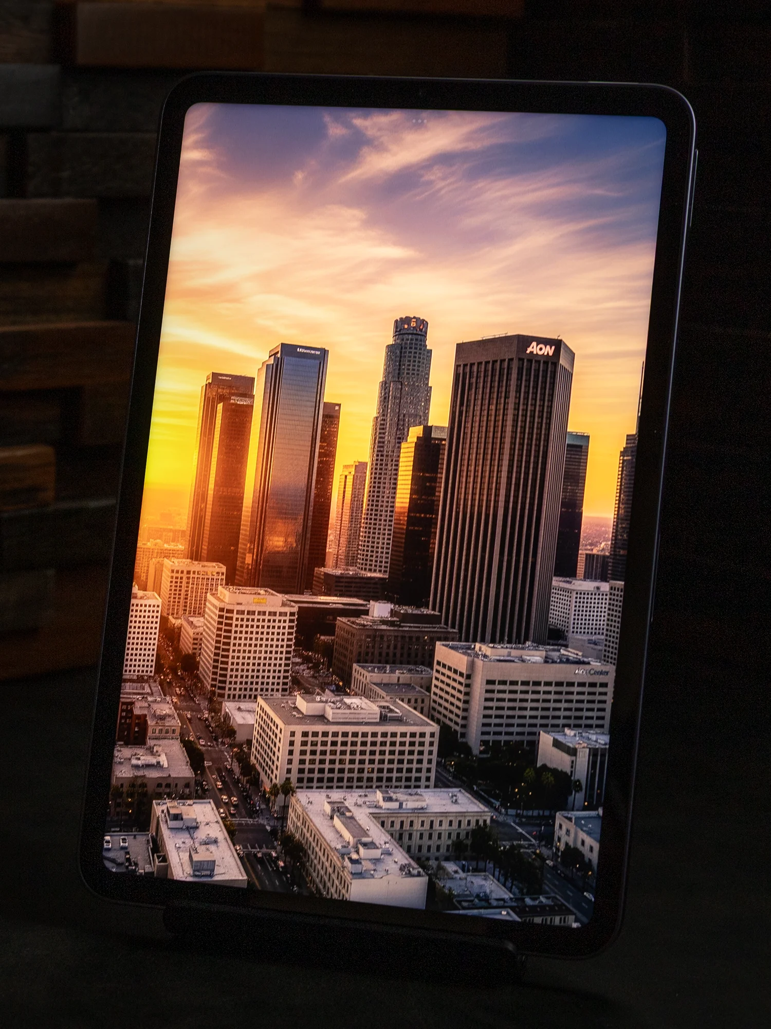 タブレットのディスプレイに表示された、夕日に照らされる高層ビル群が立ち並ぶ都市の風景写真。画面のコントラストと鮮やかな発色が強調されている。