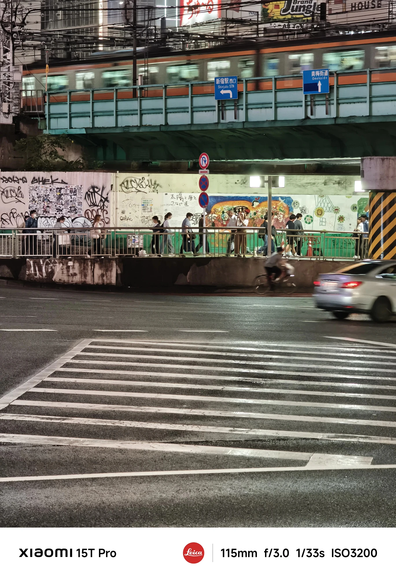 Xiaomi 15T Proで撮影した新宿駅付近の鉄道高架と交差点の夜景（115mm望遠、濡れた路面）