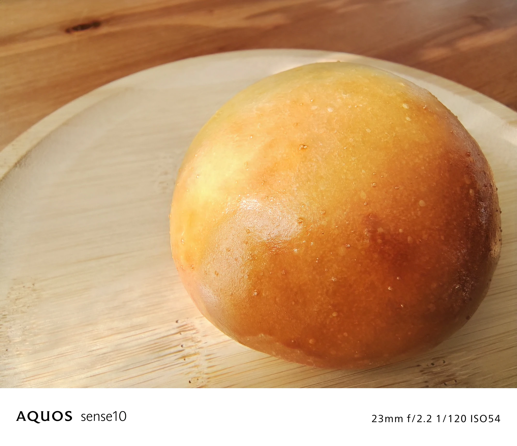 AQUOS sense10 撮影サンプル　丸いパンと木皿（クローズアップ、料理、別露出）23mm f/2.2 1/120 ISO54