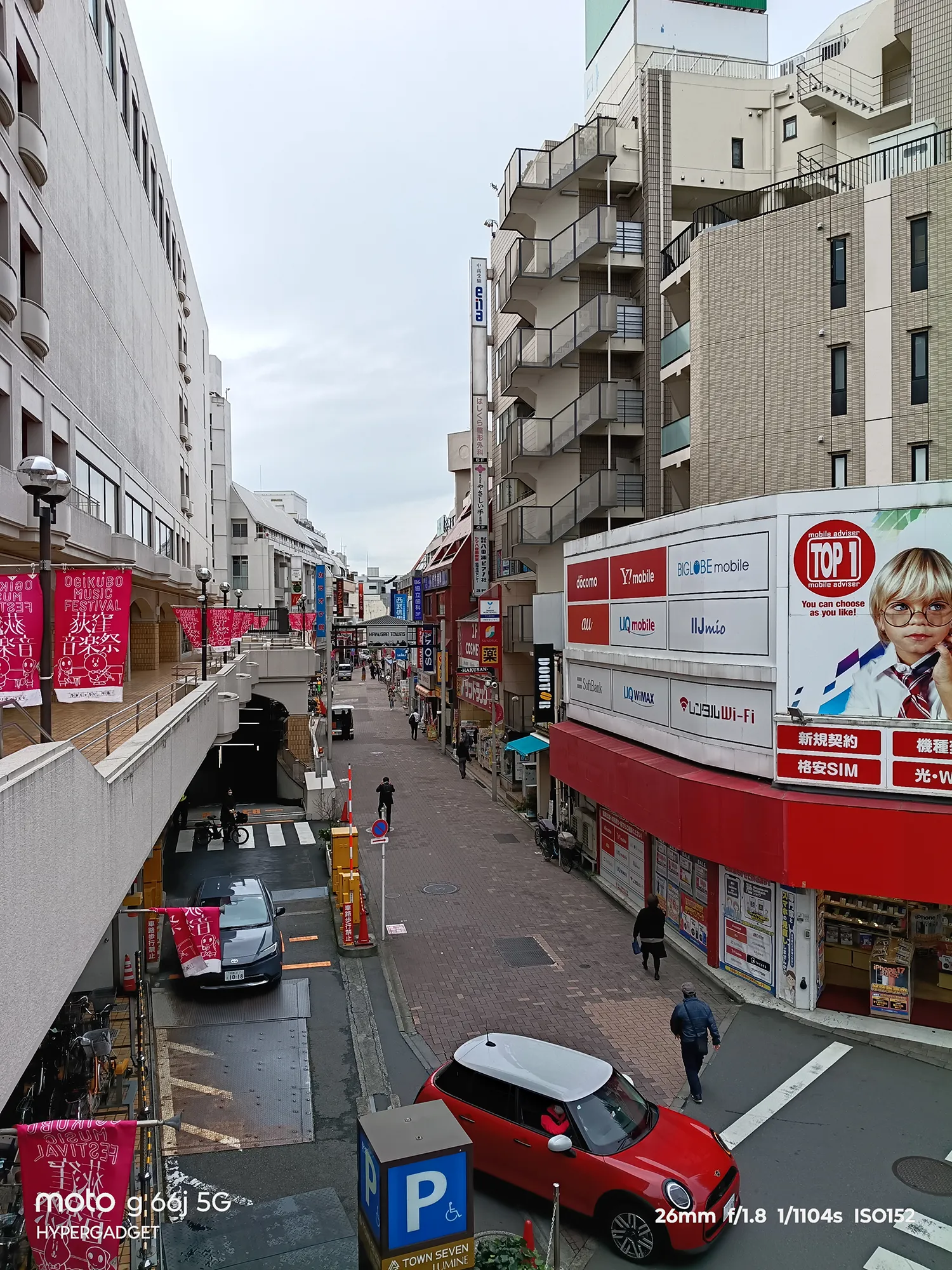 moto g66j 5Gのカメラ作例：赤いMINIが手前にある商業地内の道・商店街の俯瞰写真