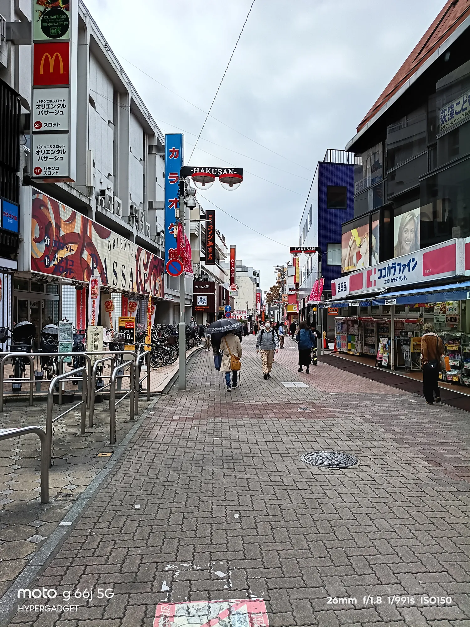 moto g66j 5Gのカメラ作例：マクドナルドやカラオケ館の看板が並ぶ、歩行者専用の商店街の遠近感のある町並み