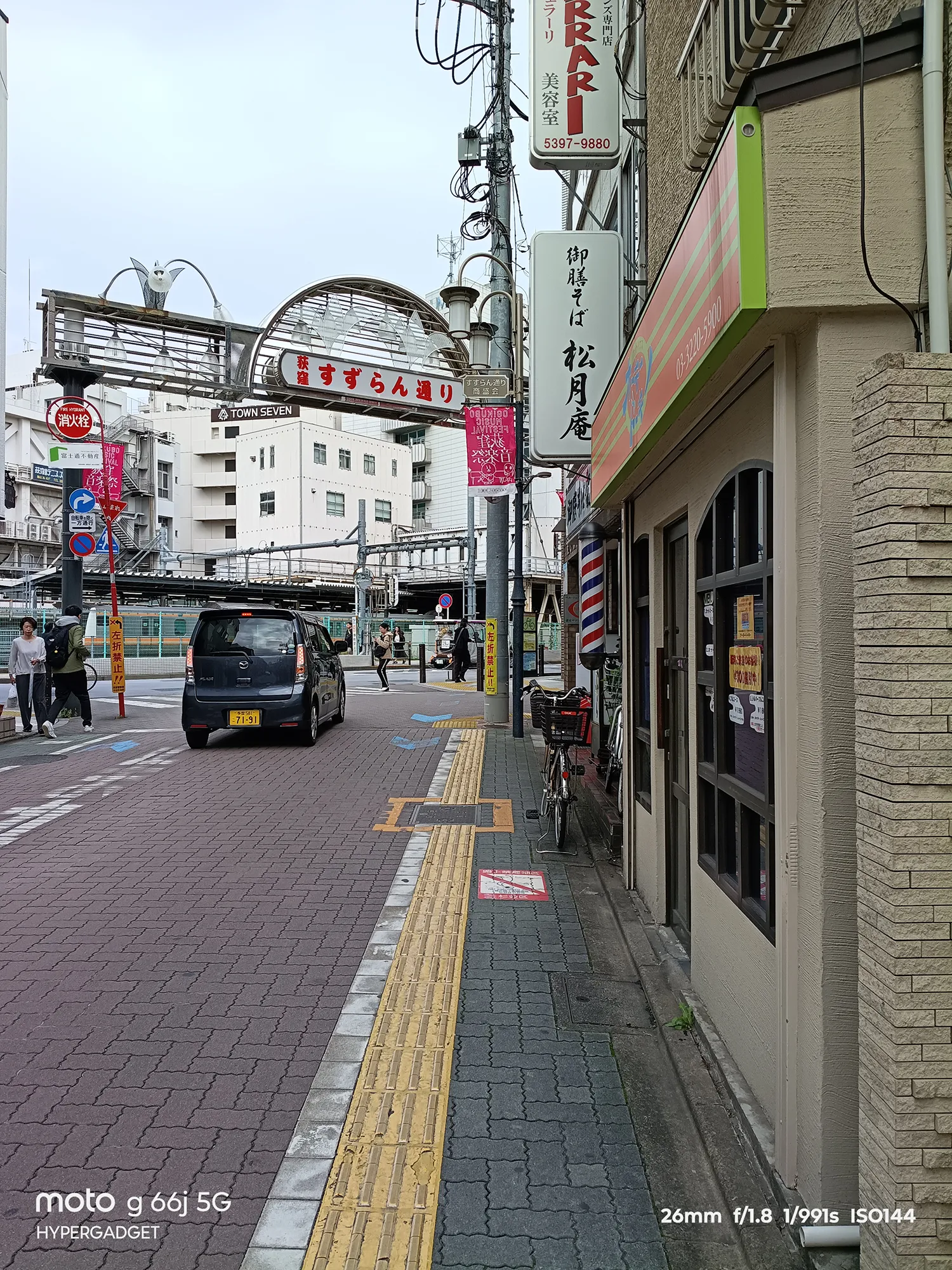 moto g66j 5Gのカメラ作例：近景の店舗と遠景の電車、すずらん通りゲートが写る複雑な都市の町並み