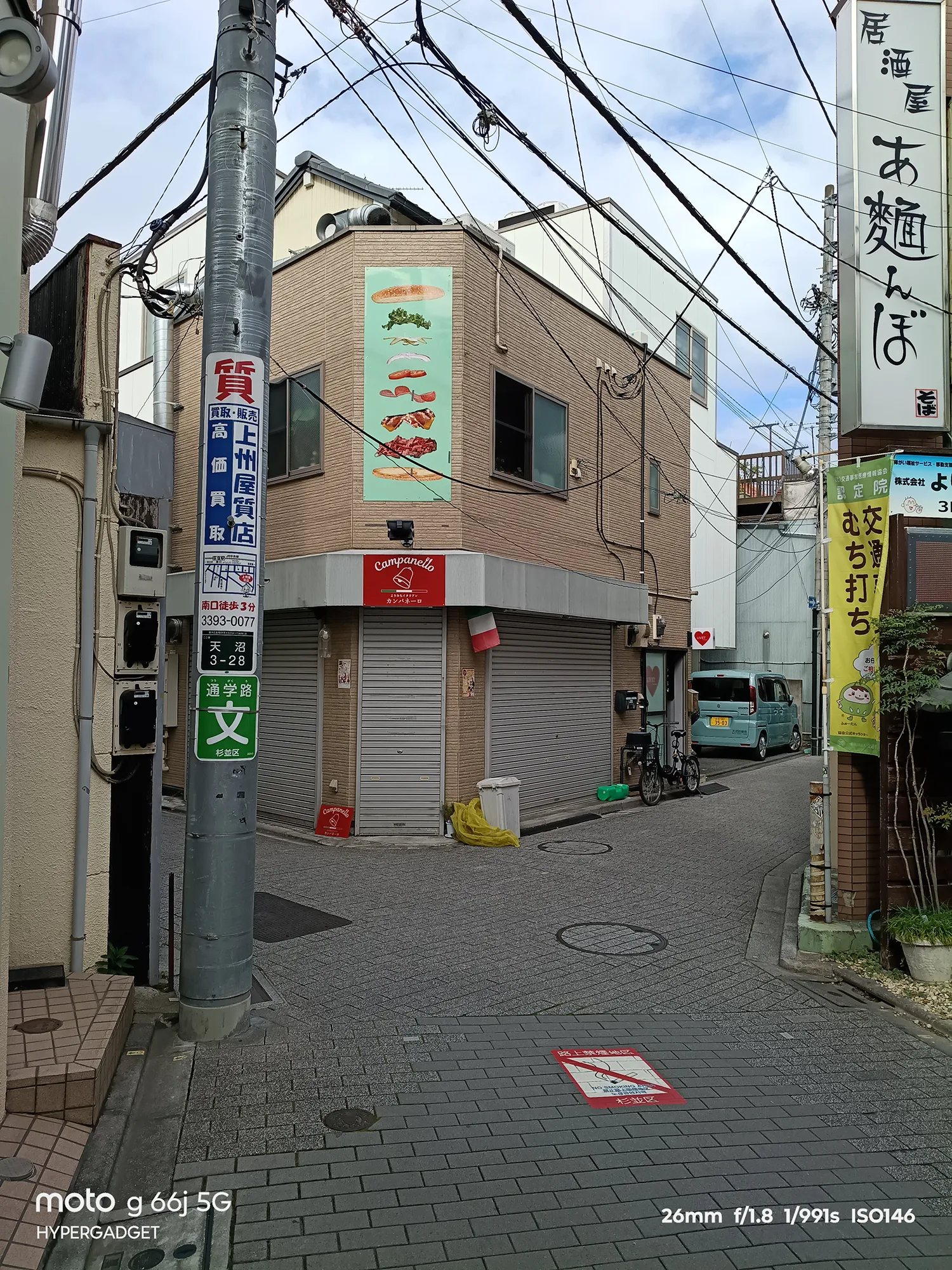 moto g66j 5Gのカメラ作例：電柱と電線が目立つ路地裏の角にあるレンガ調の建物。路地の雰囲気をレビュー