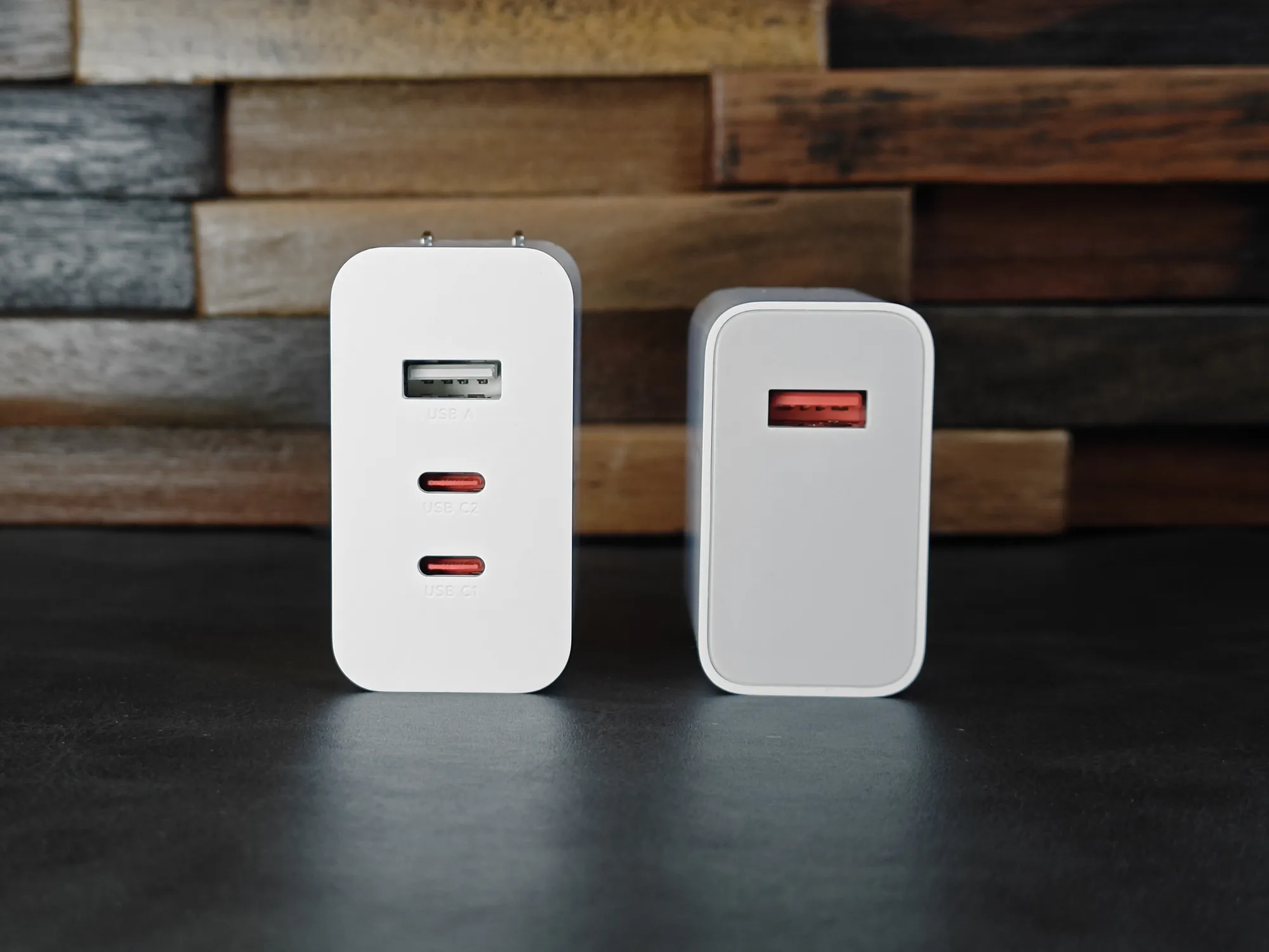 白い充電アダプター2種類をポート側から比較する写真。左側はUSB-Aポート1つとUSB-Cポート2つ（C2、C1）の計3ポートを持つマルチアダプター。右側は赤いUSB-Aポートのみを持つアダプター。