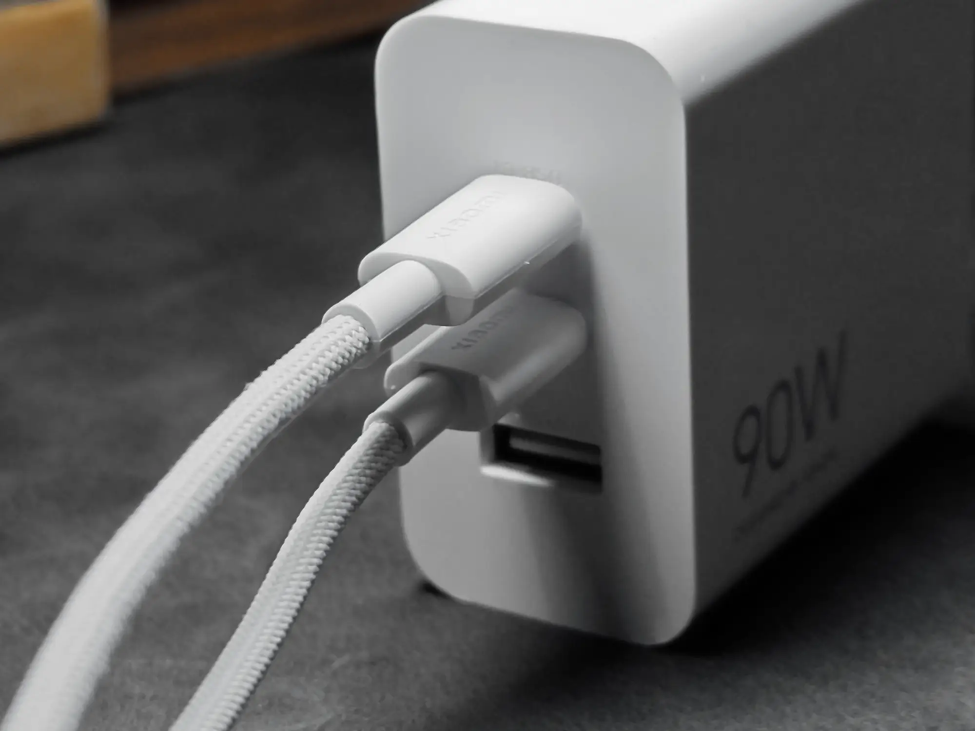 白い90W充電アダプターのUSB-Cポート2つに、白い布巻きのUSBケーブルが2本同時に接続されているクローズアップ写真。アダプターの側面には「90W」の文字が見える。2台同時充電の使用例を示す画像。