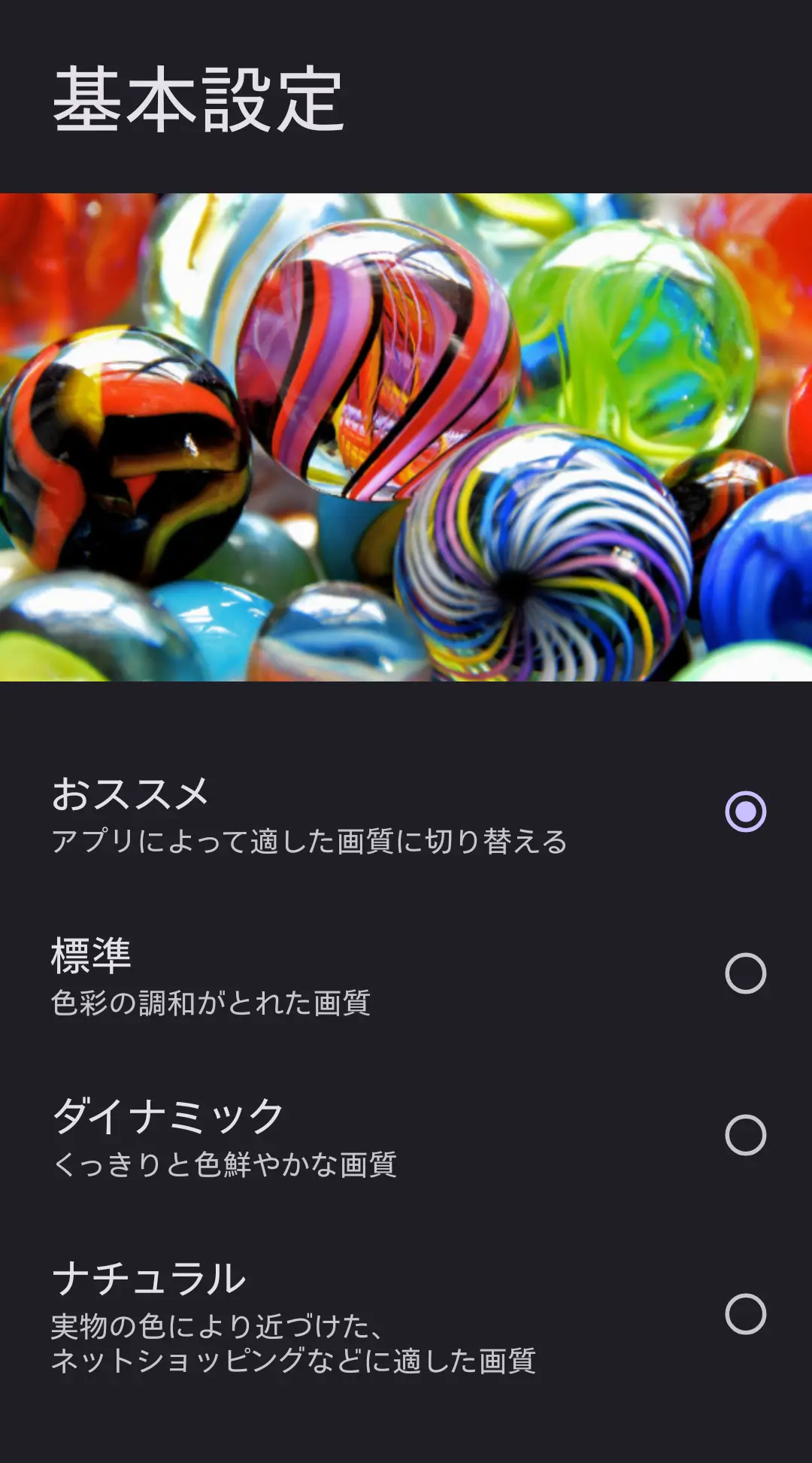 スマートフォンの「基本設定」（画質）画面のスクリーンショット。ビー玉の鮮やかな画像をサンプルに、「オススメ」「標準」「ダイナミック（くっきり鮮やか）」「ナチュラル（実物の色に近い）」といった複数の画質モードの選択肢が表示されている。AQUOSシリーズの細かな画質調整機能と、多様なユーザーニーズへの対応を示す。