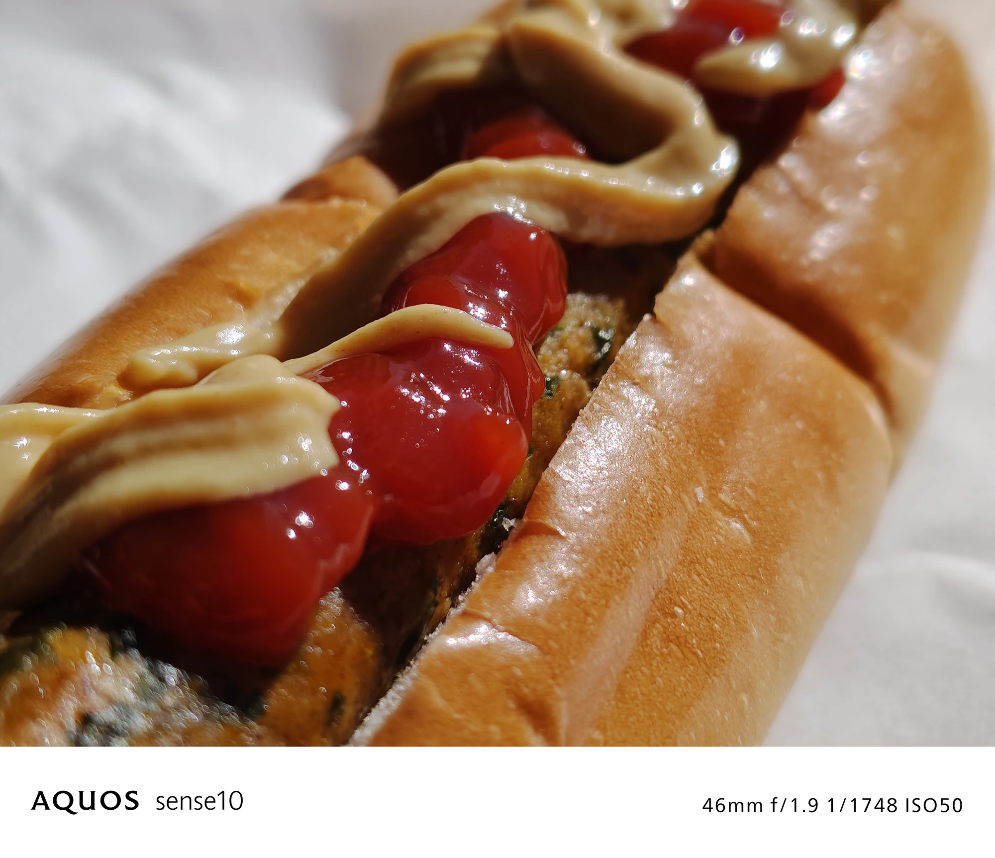 AQUOS sense10撮影サンプル：46mmズームで捉えたホットドッグのクローズアップ（f/1.9 ISO50）