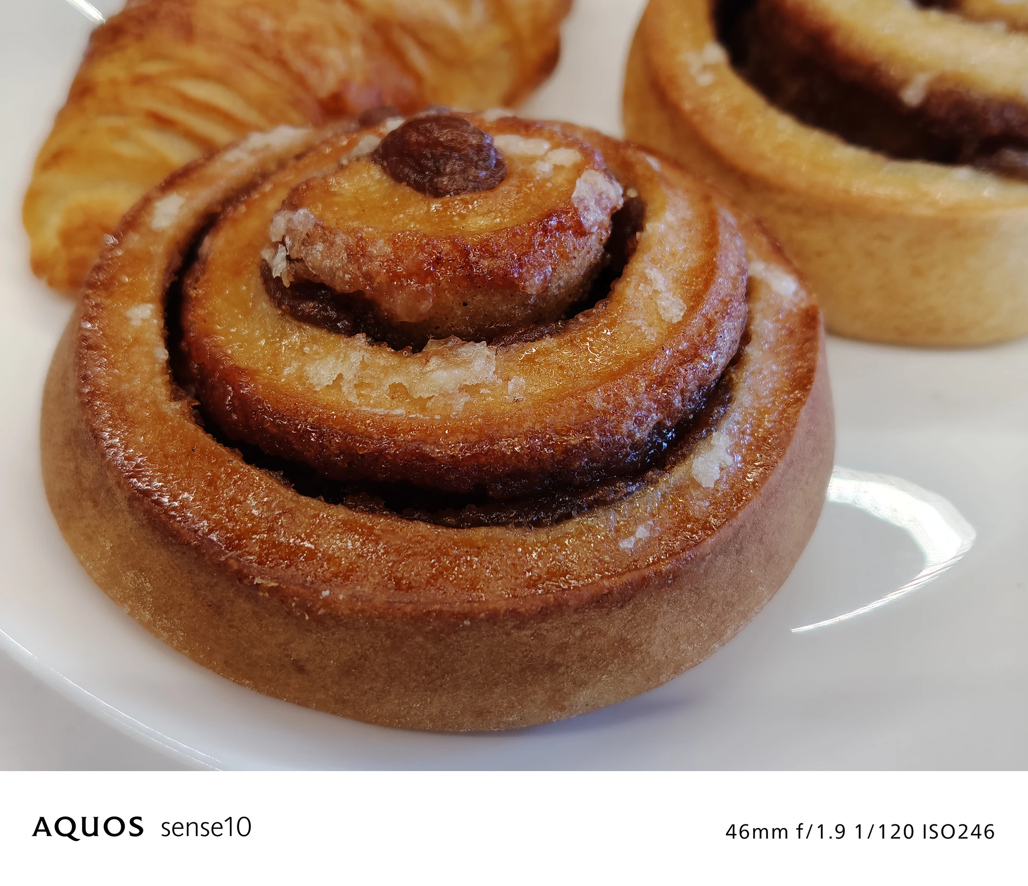 AQUOS sense10撮影サンプル：室内のシナモンロールのテーブルフォト（46mm f/1.9 ISO246）