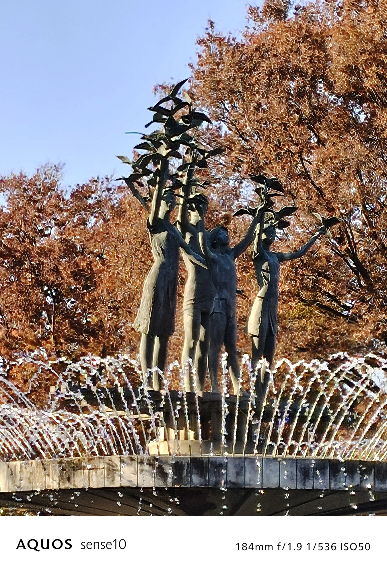 AQUOS sense10撮影サンプル：4倍ズームで捉えた**紅葉と噴水の像のアップ**（f/1.9 ISO50）