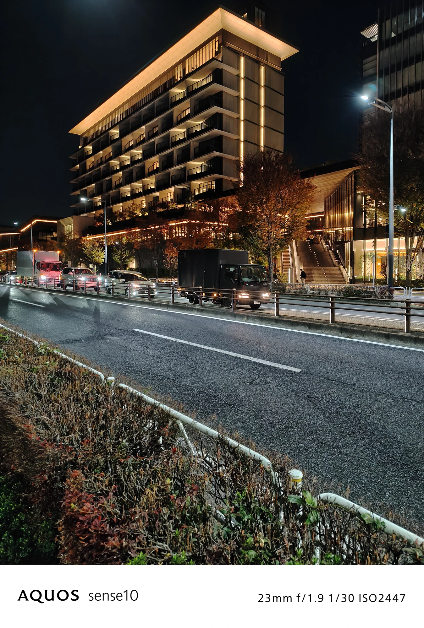 AQUOS sense10撮影サンプル：広角で捉えた**幹線道路沿いのモダンな高層ビル**（f/1.9 ISO2447）