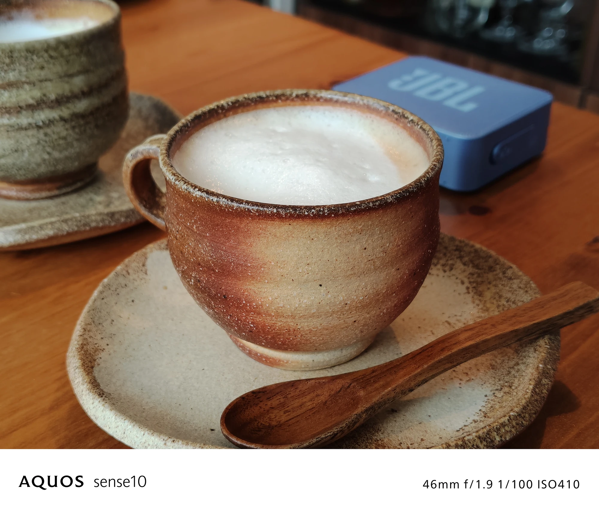 AQUOS sense10撮影サンプル：室内のカフェラテのテーブルフォト（46mm f/1.9 ISO410）