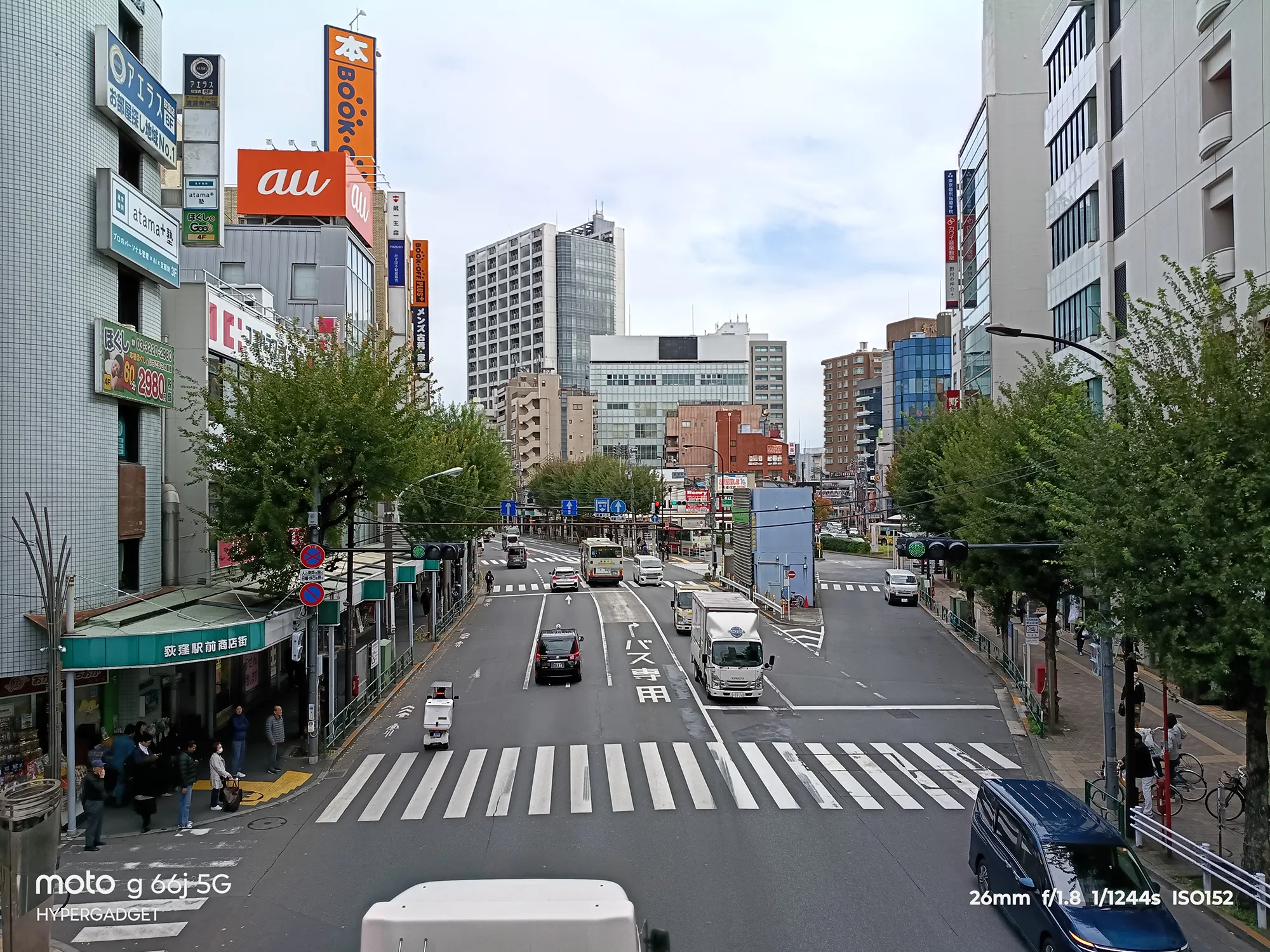 moto g66j 5Gのカメラ作例：auやBOOK OFFの看板が目立つ都市部の交差点とビル群を広角で撮影