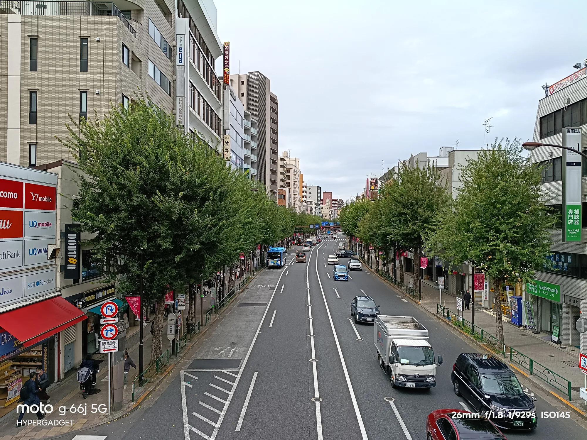 moto g66j 5Gのカメラ作例：緑の並木と車が行き交う都市の広い通りを俯瞰で撮影した町並み写真