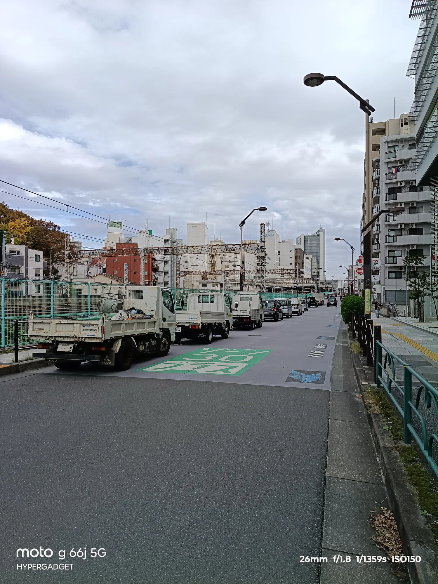 moto g66j 5Gのカメラ作例：トラックが並ぶ都心の道路と、奥の建物、高架の鉄道線を写した町並み写真