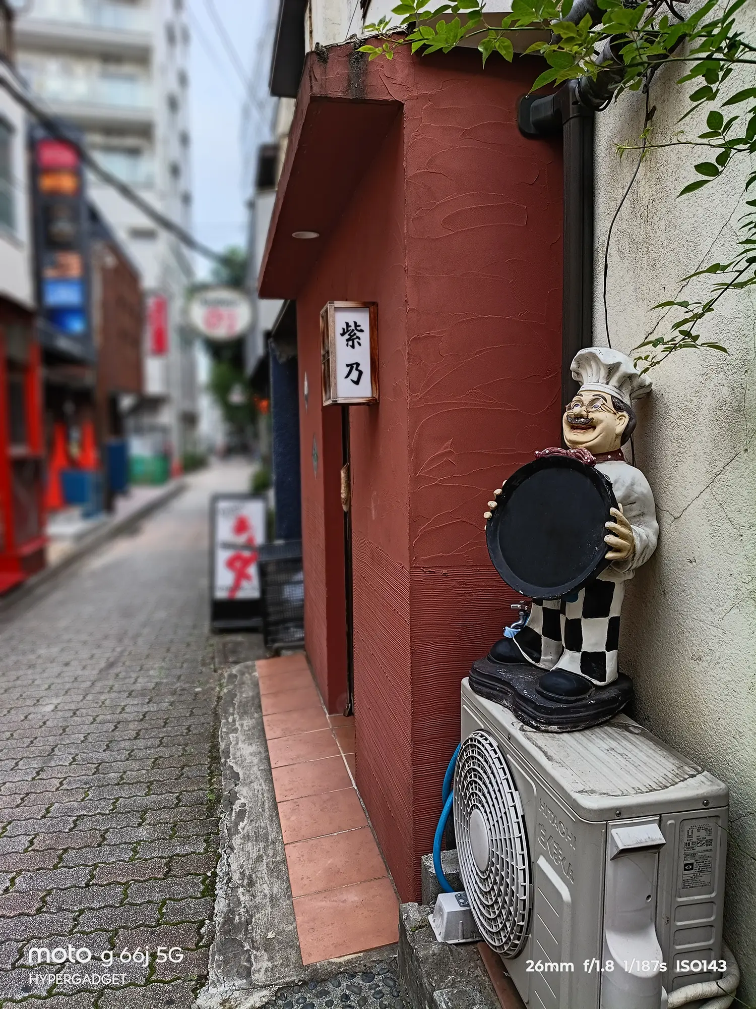 moto g66j 5Gのカメラ作例：赤い壁の飲食店とコックの置物を近接撮影。背景のボケ味と色再現性をレビュー