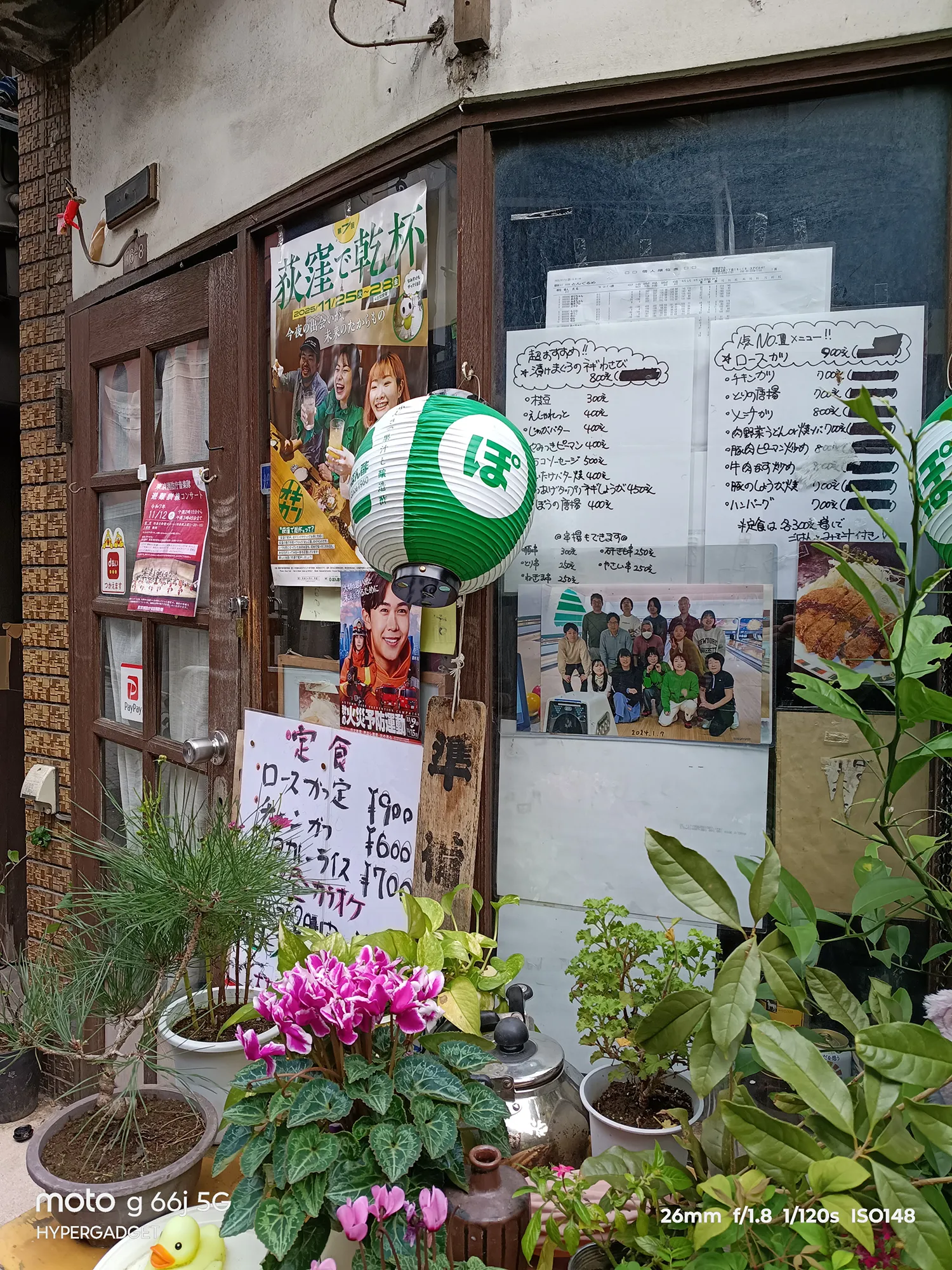 moto g66j 5Gのカメラ作例：植木鉢と手書きメニュー、ポスターがある店舗の窓際。複数の要素と文字の可読性をレビュー