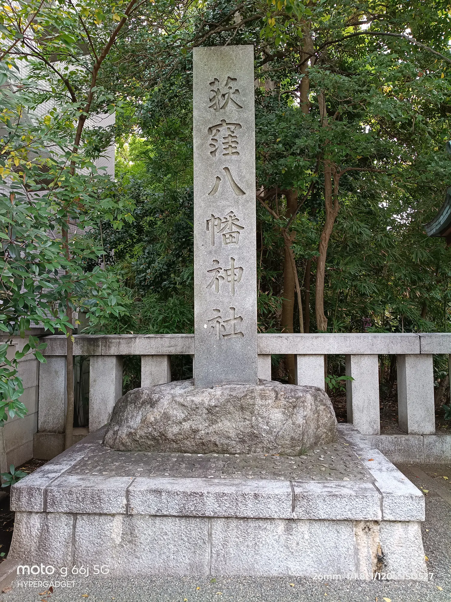 moto g66j 5Gのカメラ作例：緑の木々に囲まれた荻窪八幡神社の石碑を撮影。石材の質感と文字の明瞭さをレビュー