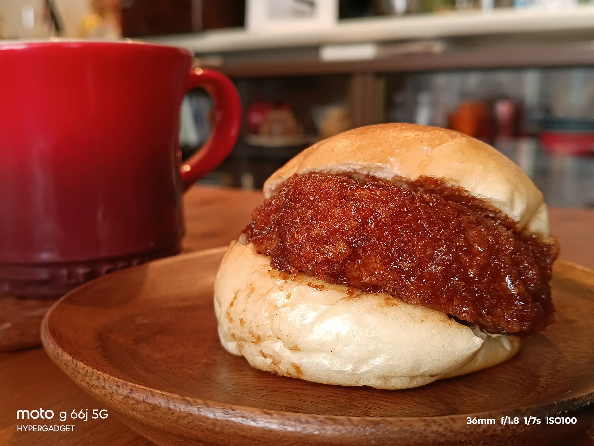 moto g66j 5Gのカメラ作例：木皿に載ったメンチカツサンドと赤いマグカップをクローズアップ。揚げ物の質感とボケ味をレビュー