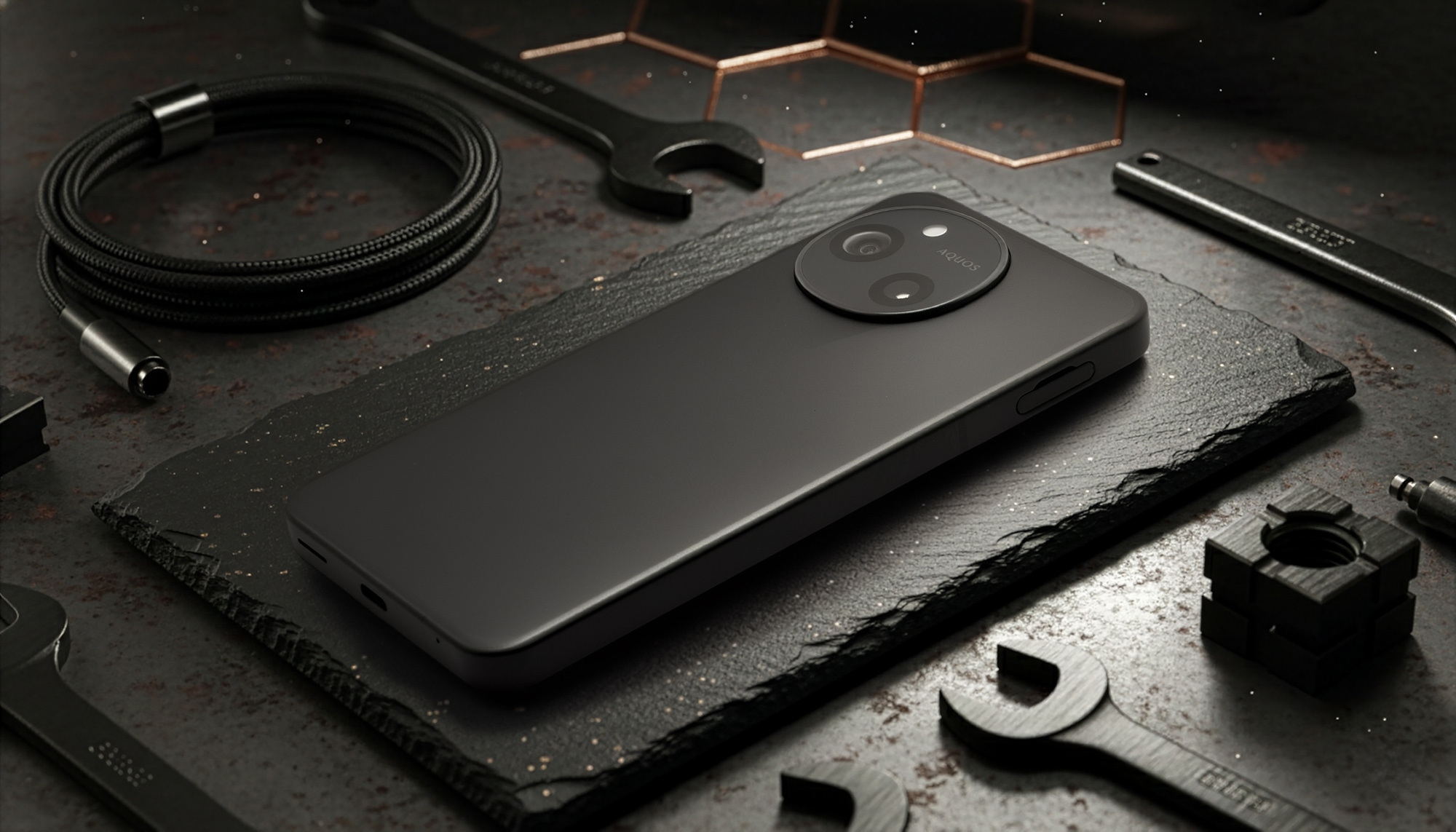 AQUOS sense10の背面を映した、マットブラックの製品写真。特徴的な円形のカメラモジュールと、その内部に配置されたデュアルカメラが見える。工業的なデザインを強調するため、背景にはスパナやケーブルなどの工具が配置されている。洗練されたデザインとカメラユニットの存在感をアピール。