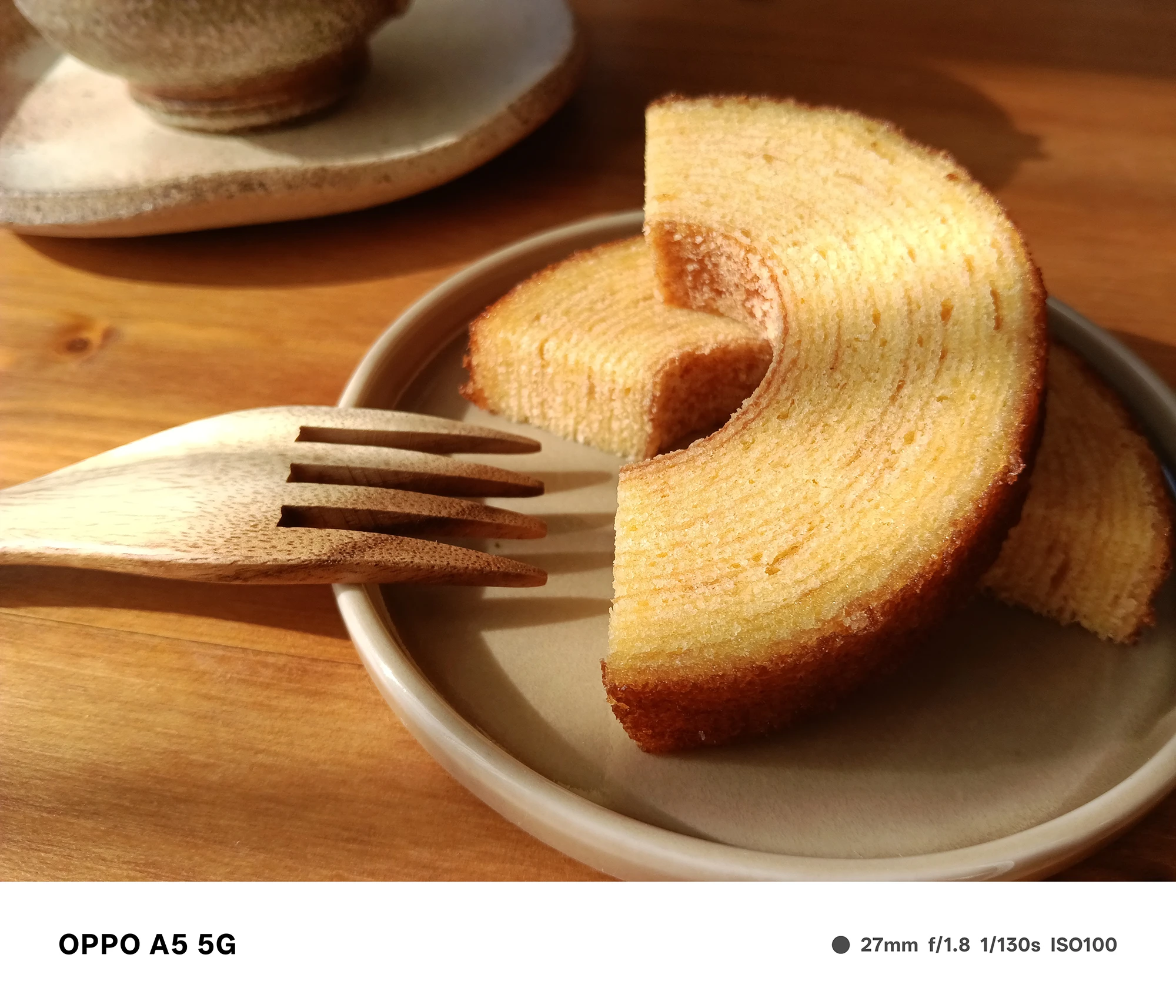 OPPO A5 5Gで撮影したバウムクーヘンの食品作例。自然光に照らされた生地の層と木の温かみある食卓を丁寧に描写