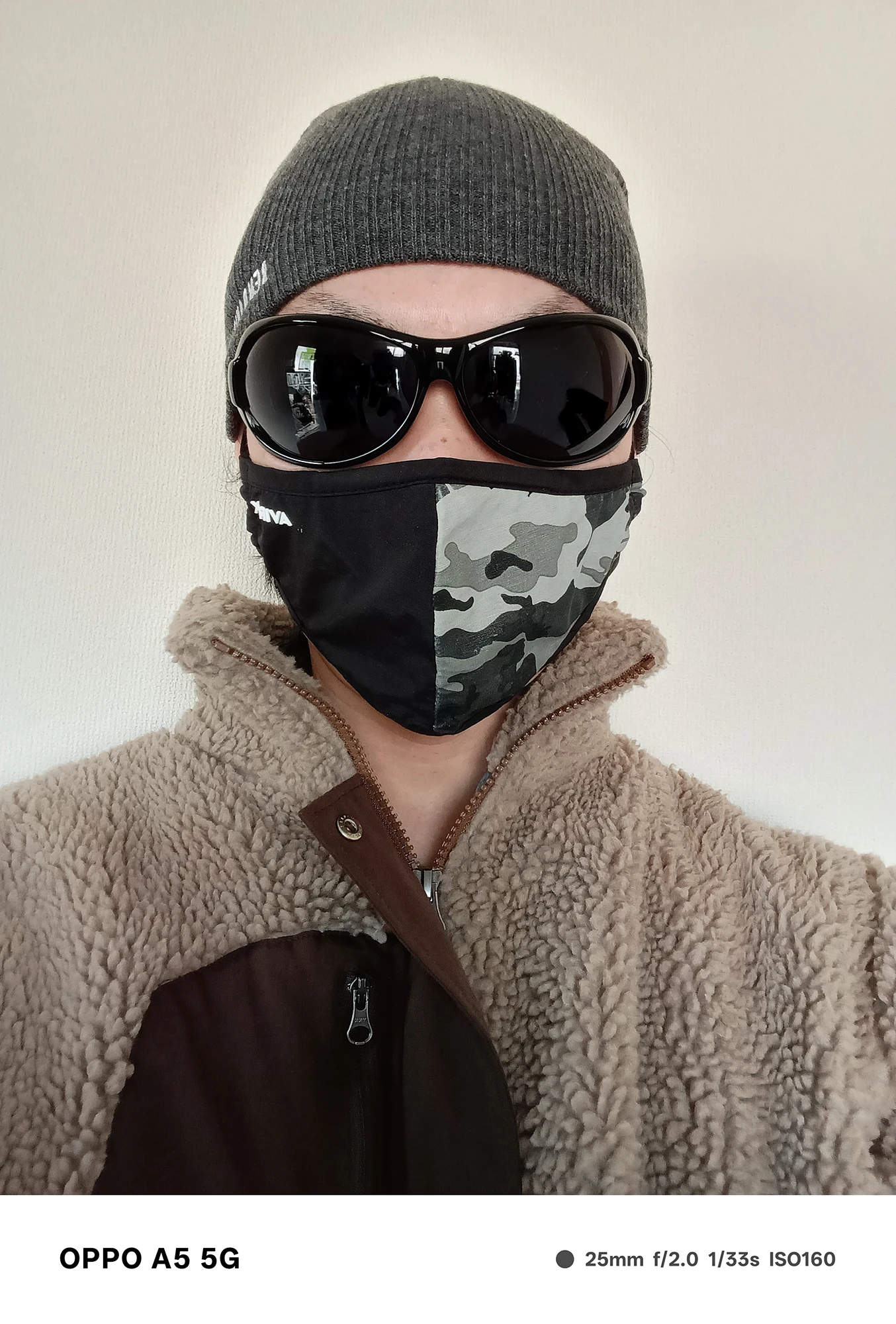 OPPO A5 5Gで撮影した人物のセルフィー。帽子・サングラス・マスクを着用し、シンプルな室内背景で撮影された作例