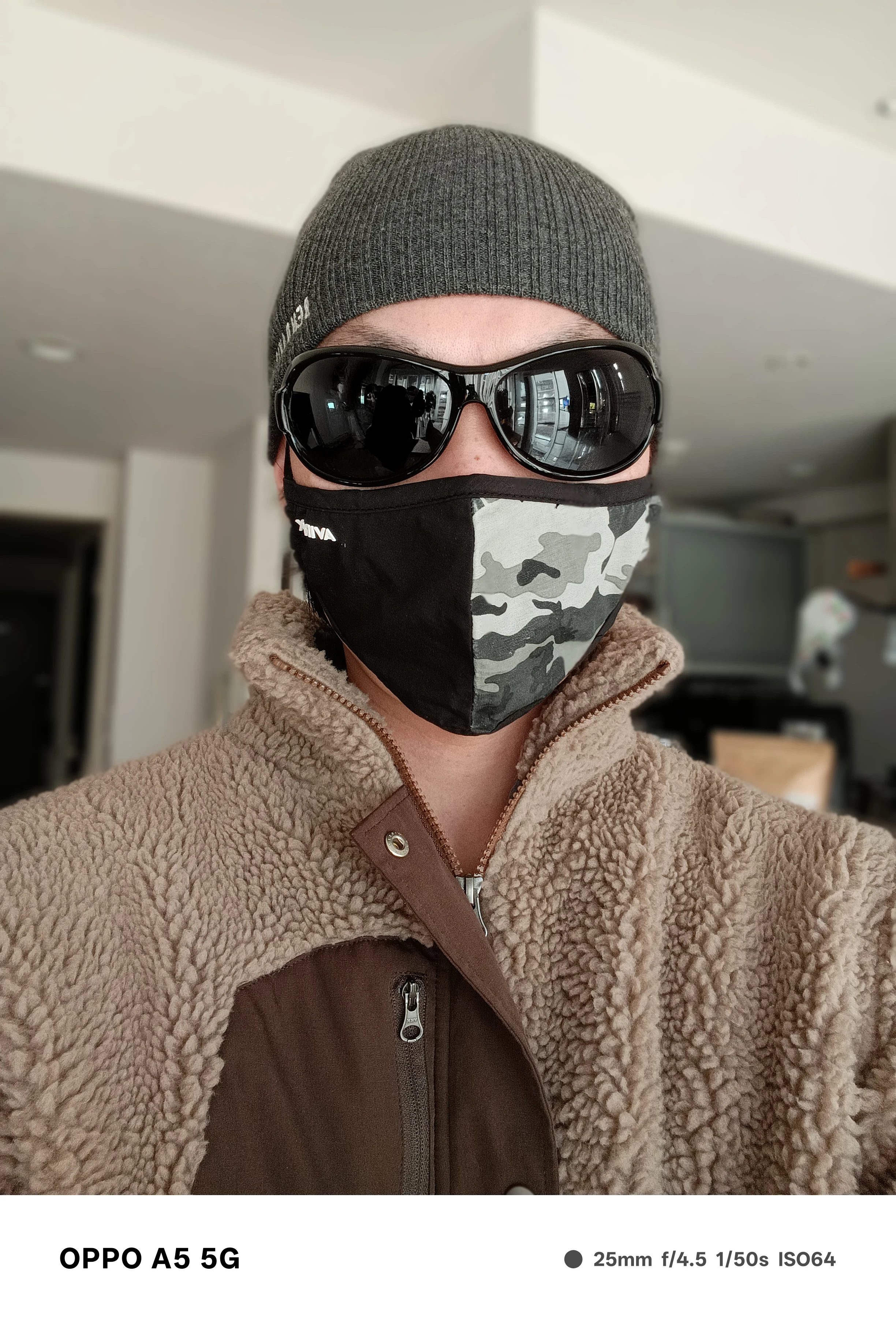 OPPO A5 5Gのポートレートモードで撮影した人物のセルフィー。帽子とサングラスを着用し、背景が大きくぼけた室内作例