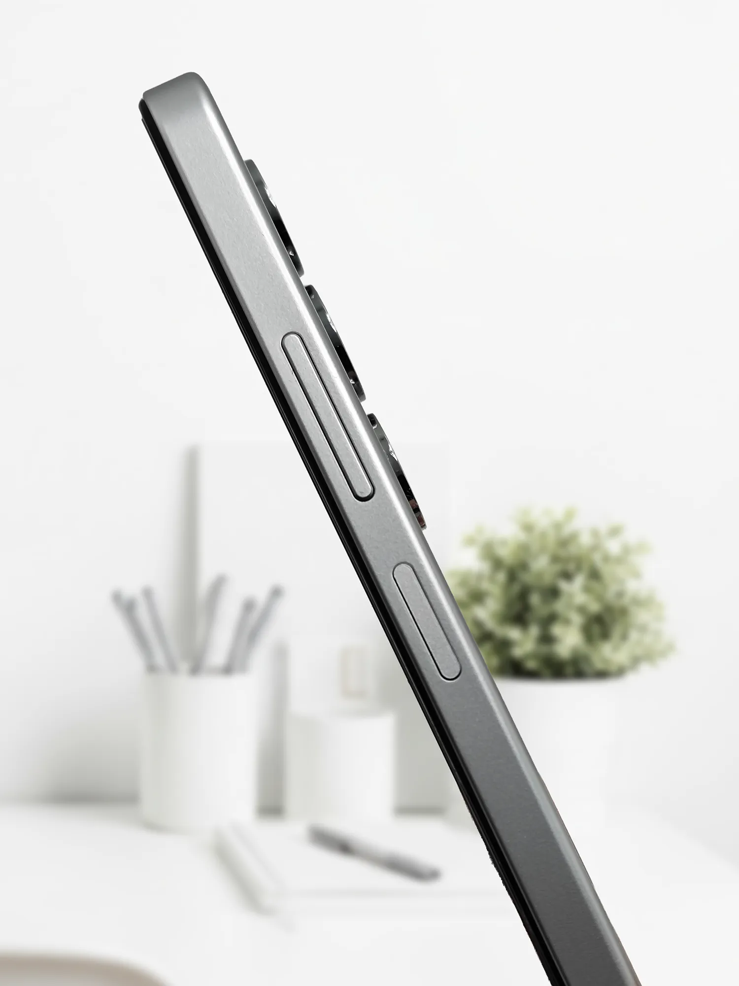 クリーンな屋内環境を背景に撮影された、OPPO A5 5Gの側面のクローズアップ写真。メタリックなフレームには、上下に分かれた音量ボタンと、その下にある電源/指紋認証ボタンが見える。