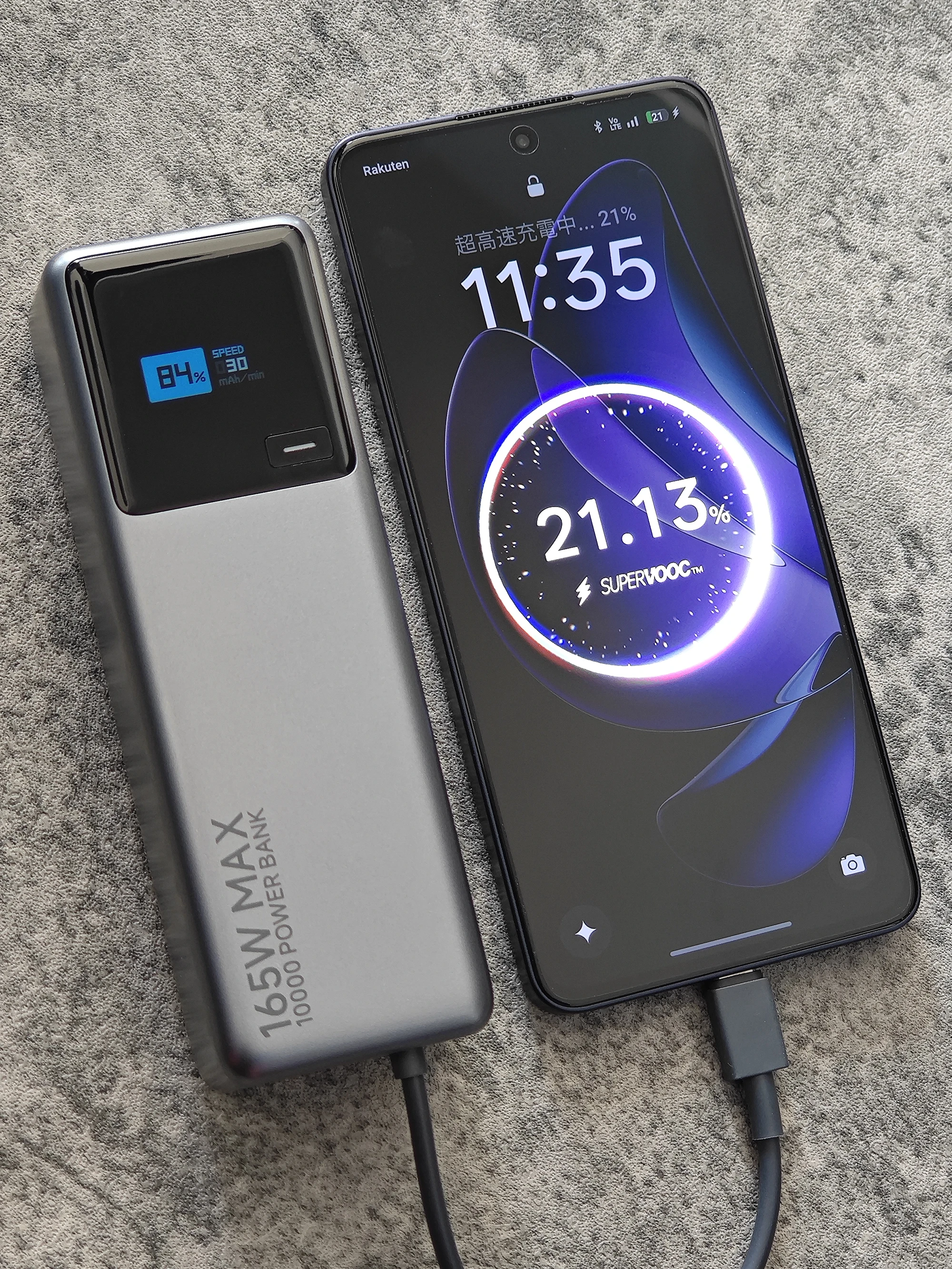 OPPO Reno13 Aをモバイルバッテリーから充電する様子。SUPERVOOC表示と残量21.13%、165W MAX表示のバッテリーを並べて撮影