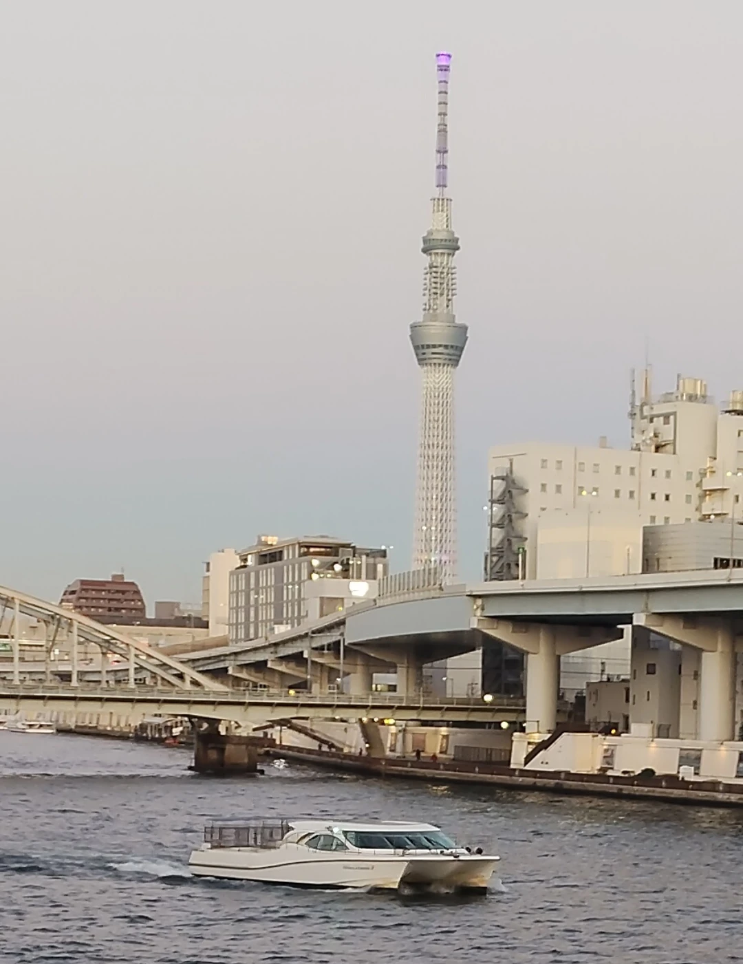 隅田川沿いの風景。スカイツリーと船、橋梁を1枚に収めた望遠ショット。