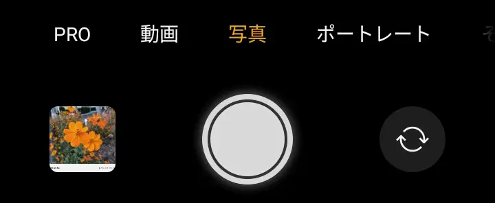 OPPO A5 5Gのカメラアプリ画面。画面上部に「PRO」「動画」「写真」「ポートレート」のモード選択タブが表示され、「写真」モードが選択中。左下には撮影されたオレンジ色のコスモスの写真が見える。