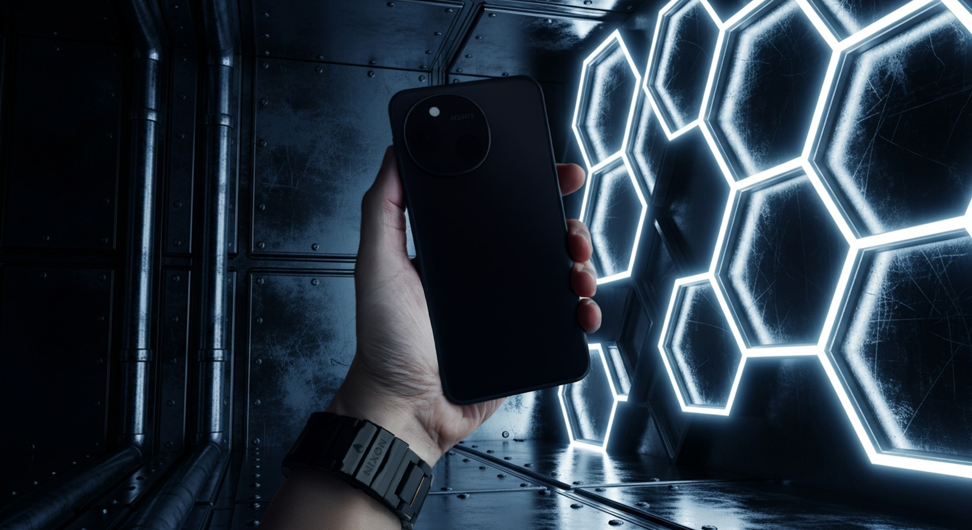 近未来的なLEDパネルが並ぶ暗い金属空間で、手に持った黒いAQUOSスマートフォンの背面デザインを撮影したイメージ。大型円形カメラユニットとシンプルな背面仕上げが強調されたクールでハイテク感のある構図。