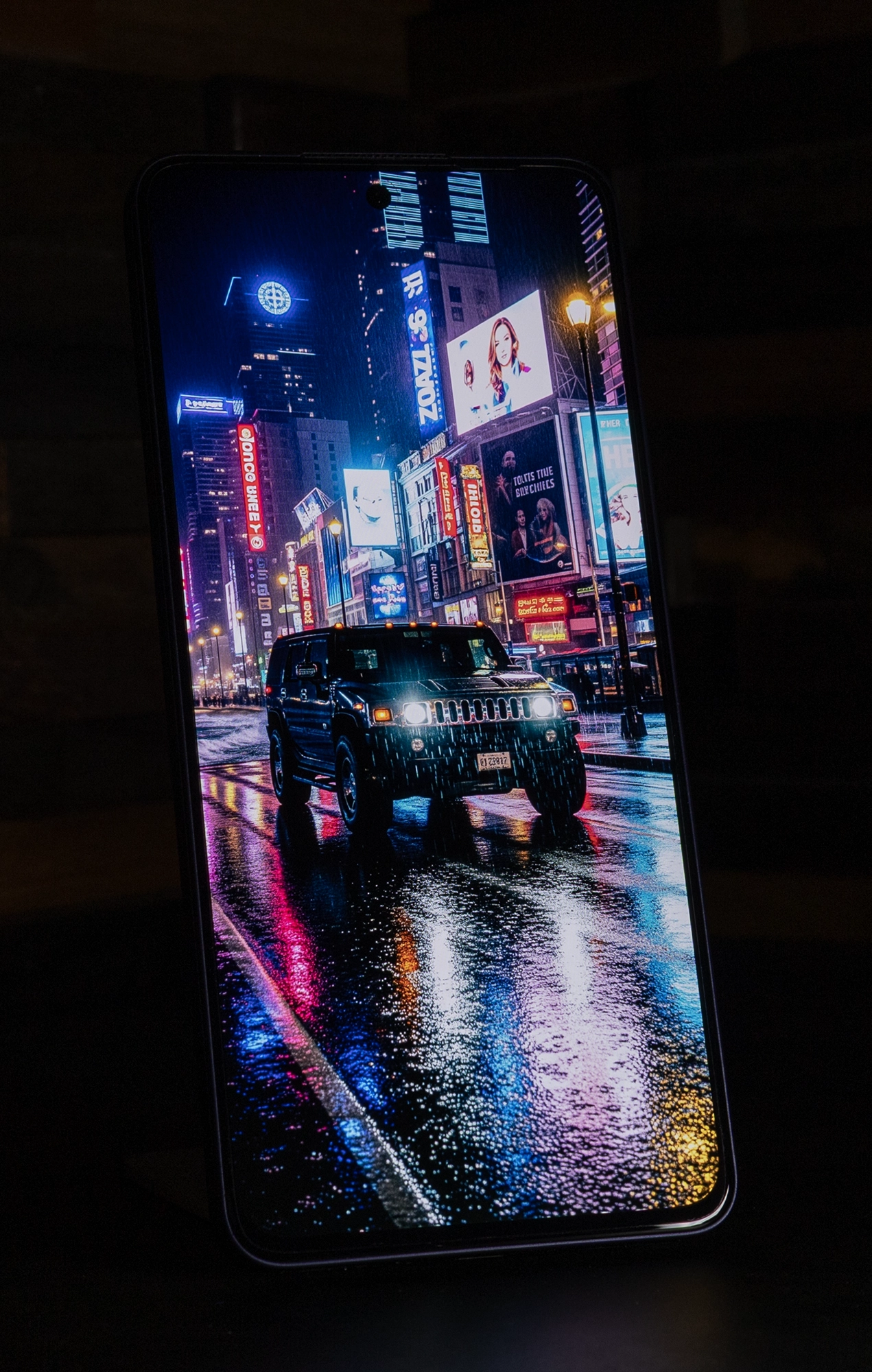 OPPO Reno13 Aのディスプレイに映し出された、雨に濡れた夜のタイムズスクエアのような街並みと車の画像