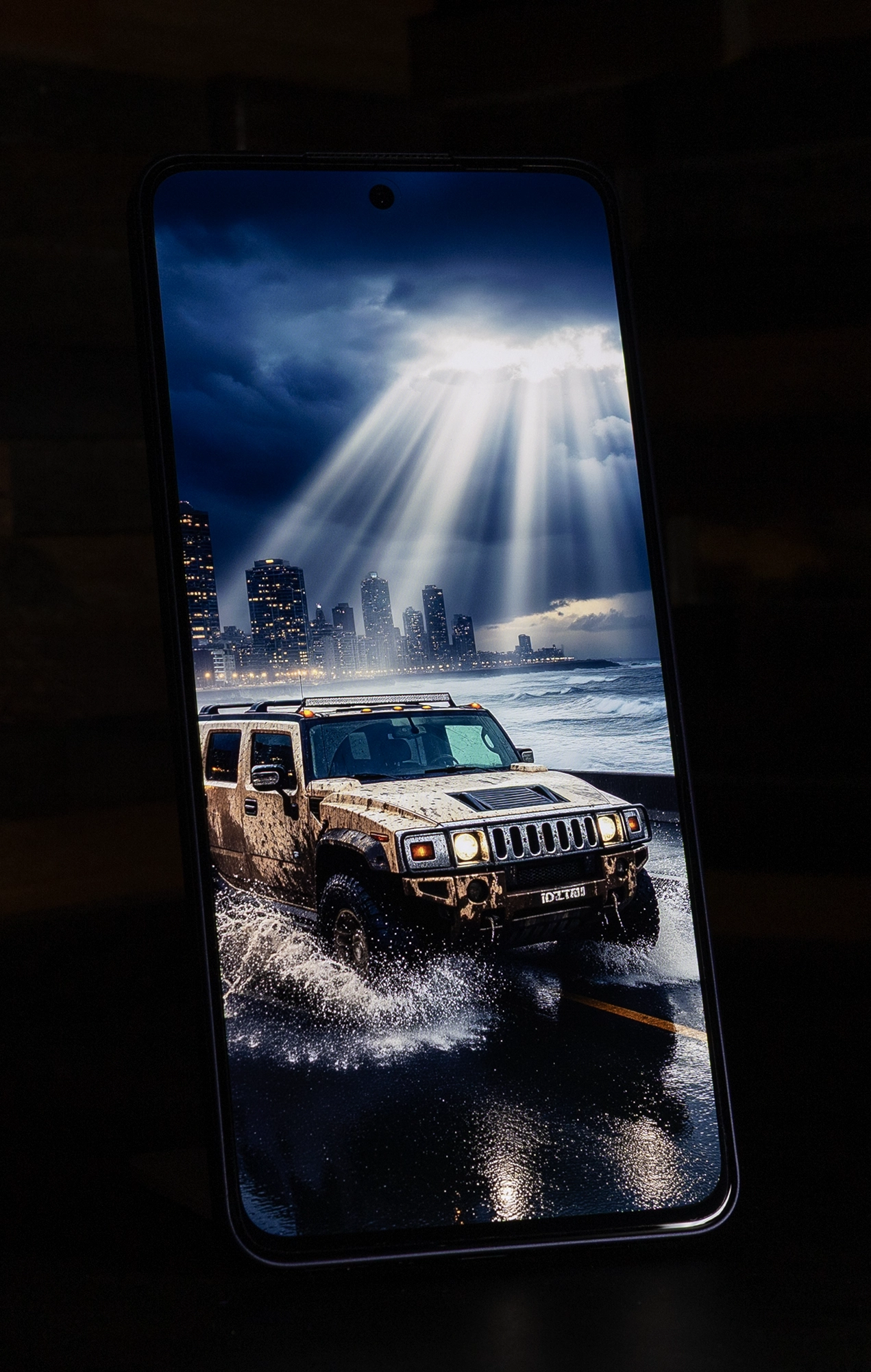 OPPO Reno13 Aのディスプレイに映し出された、厚い雲間から差し込む光の下を走行するオフロード車の画像