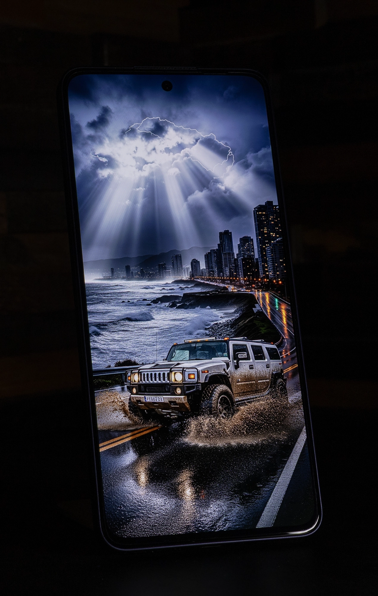 OPPO Reno13 Aのディスプレイに映し出された、夜の海岸沿いを走行するオフロード車と雷雲の画像